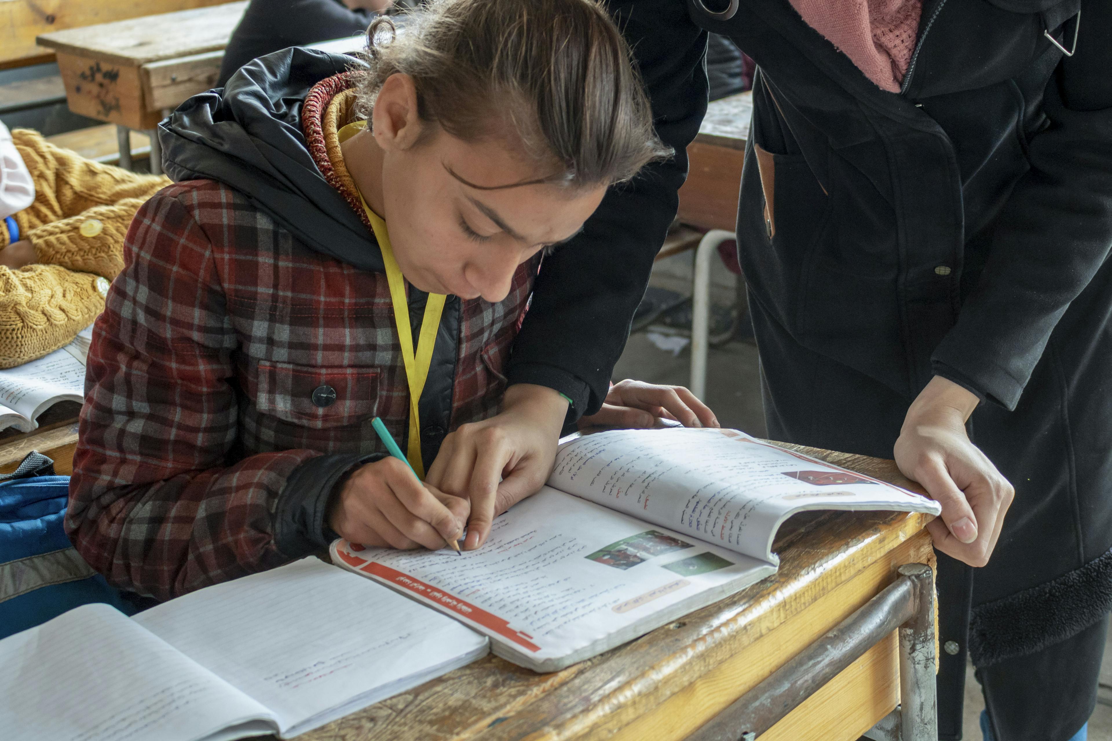 Fatima receiving help from a teacher in class. She now looks forward to going to school and is enthusiastic about completing her school work.