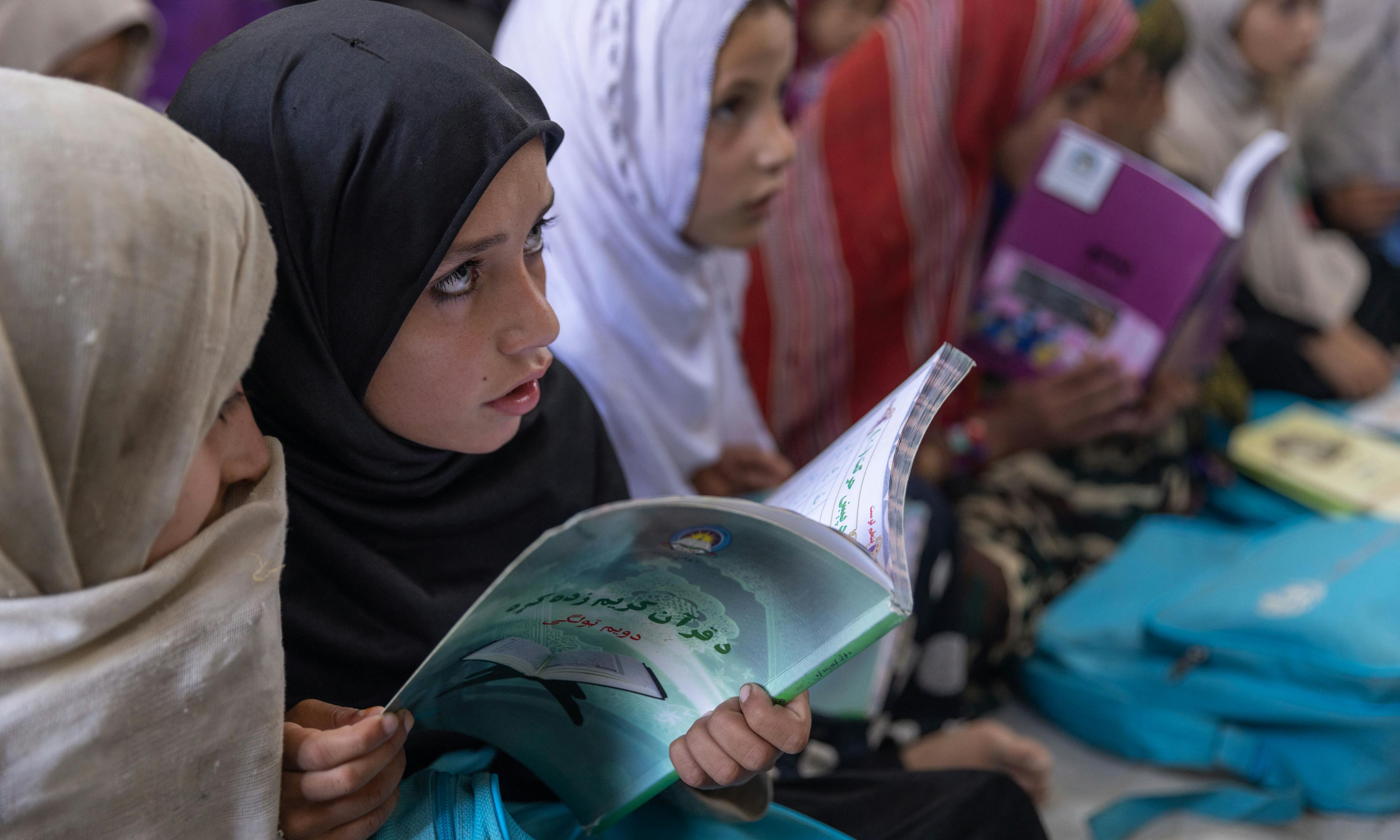 Inside her new classroom, Gulaba, 9, studies from her textbook alongside her classmates.