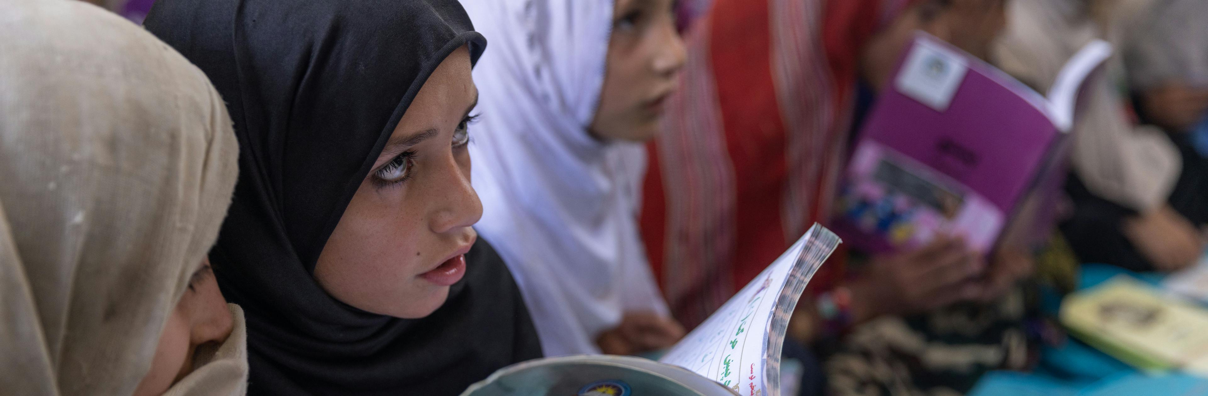 Inside her new classroom, Gulaba, 9, studies from her textbook alongside her classmates.