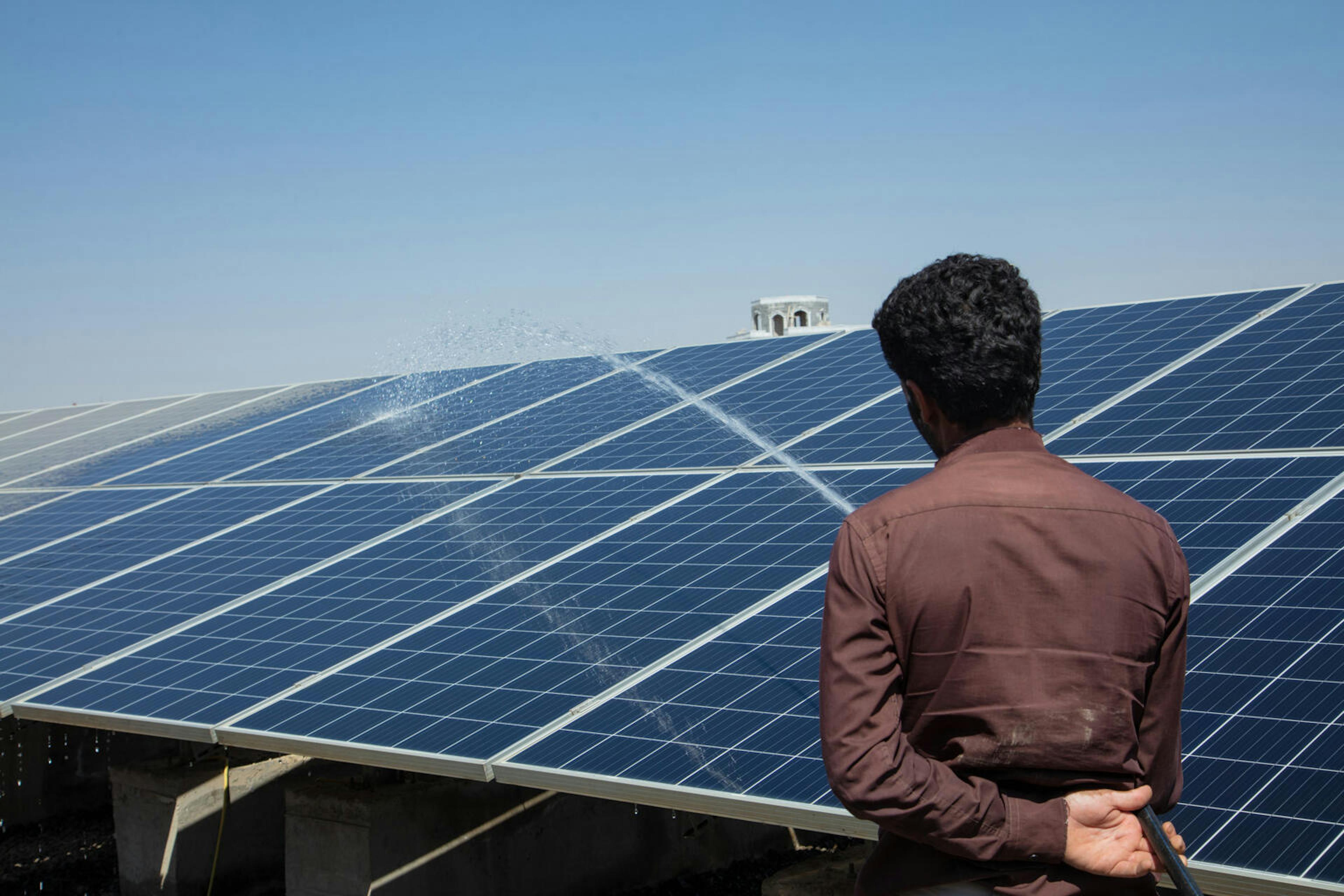 A staff member washes the solar panels at the Local Corporation for Water and Sanitation in Dhamar Governorate, Yemen.