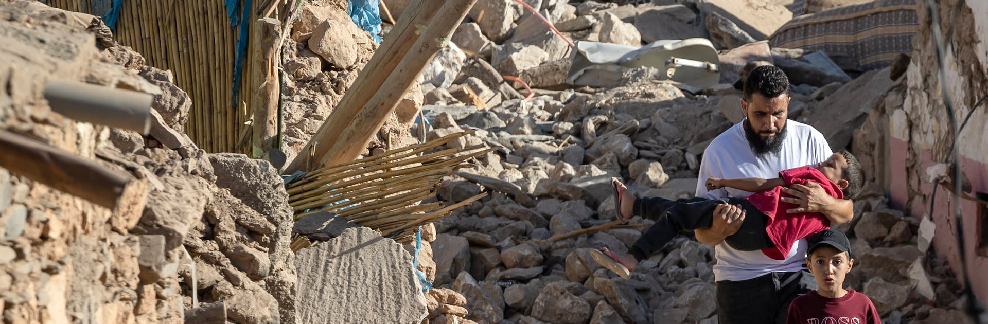 People walk past destroyed houses after an earthquake in the mountain village of Tafeghaghte, southwest of the city of Marrakesh, on September 9, 2023.