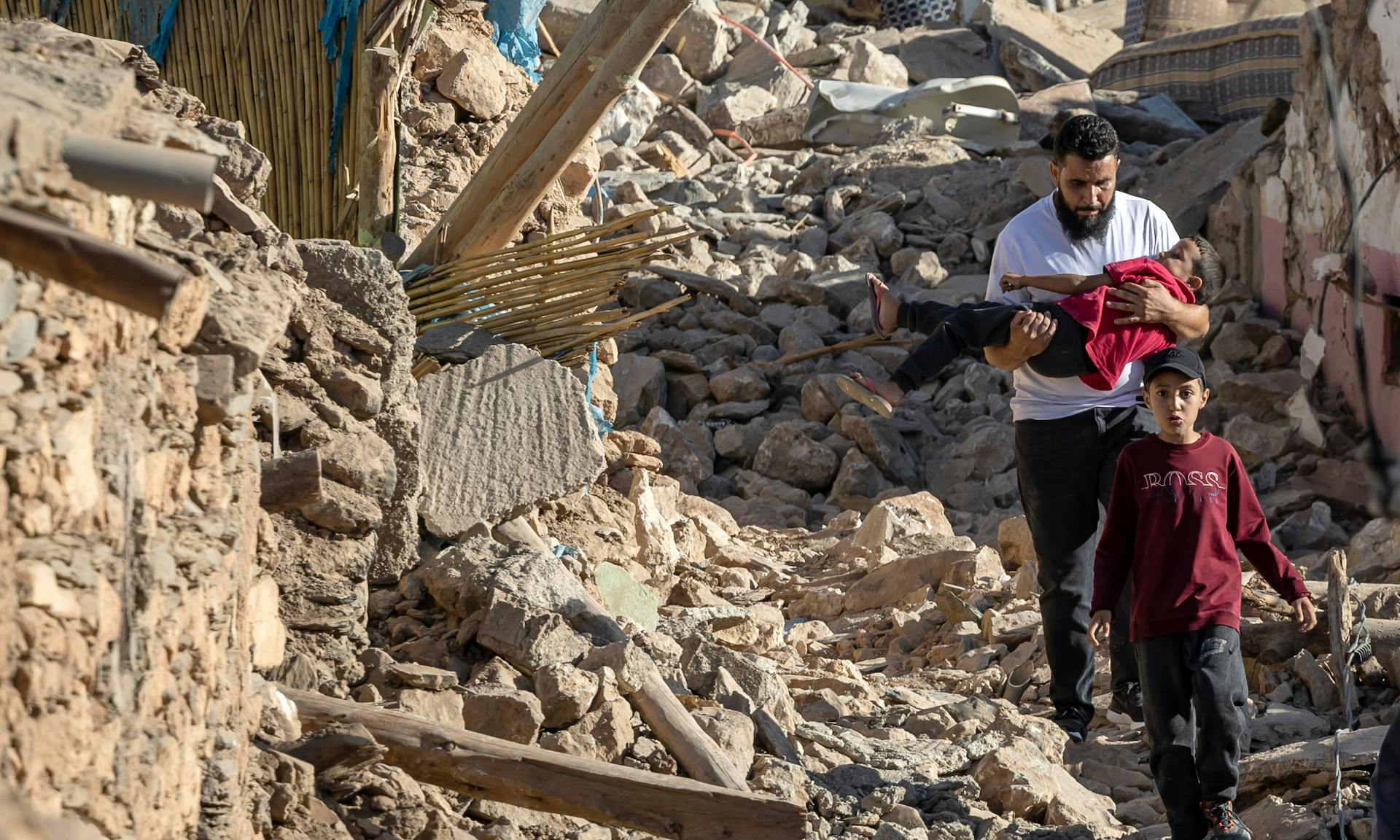 People walk past destroyed houses after an earthquake in the mountain village of Tafeghaghte, southwest of the city of Marrakesh, on September 9, 2023.