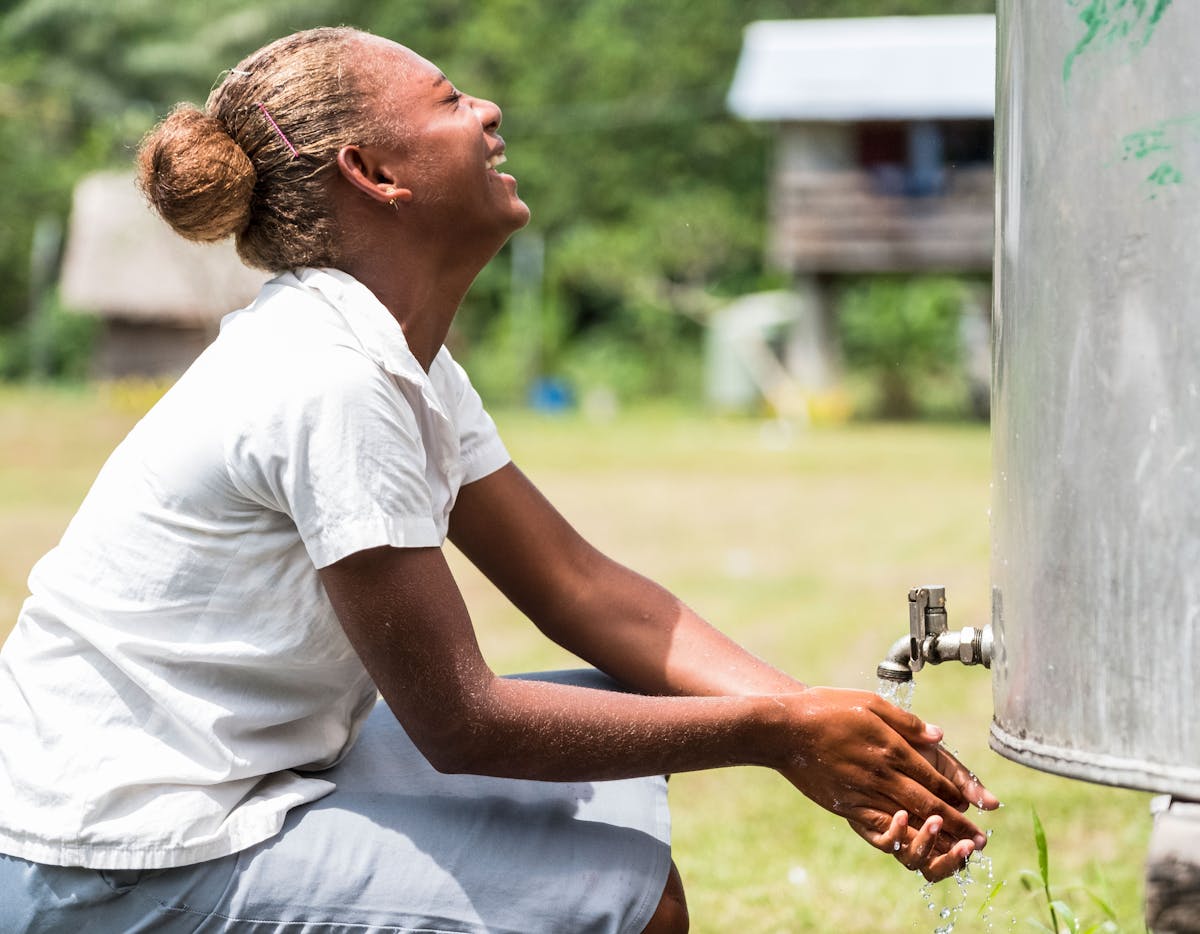 A school girl laughs while washing her hands with clean water