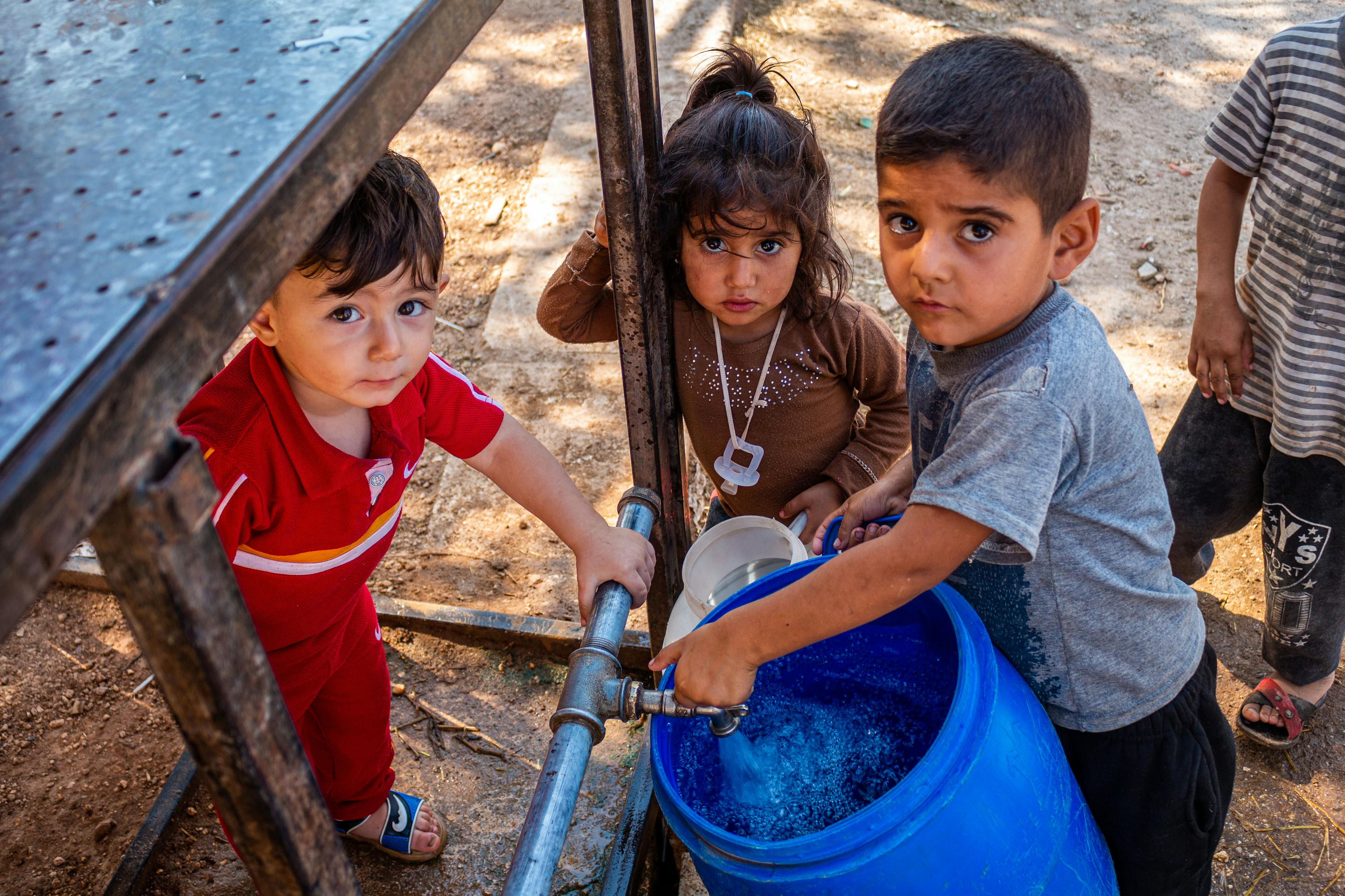 A group of children fill up a bucket with clean water from a tap installed by UNICEF