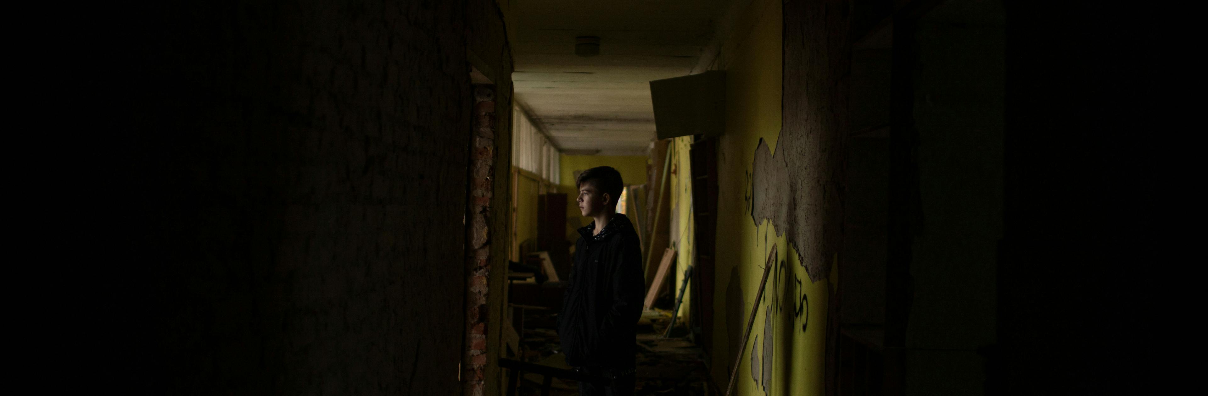A young boy standing in the hallway of a destroyed school in Ukraine