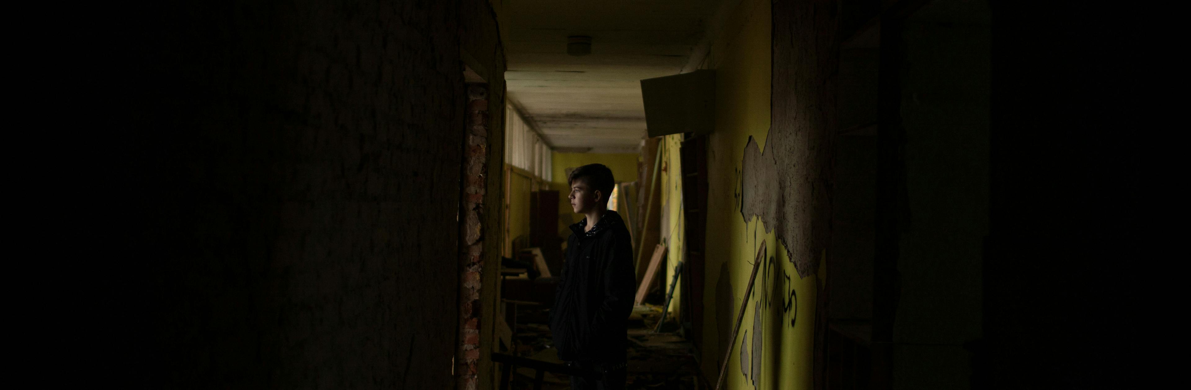 A young boy standing in the hallway of a destroyed school in Ukraine 