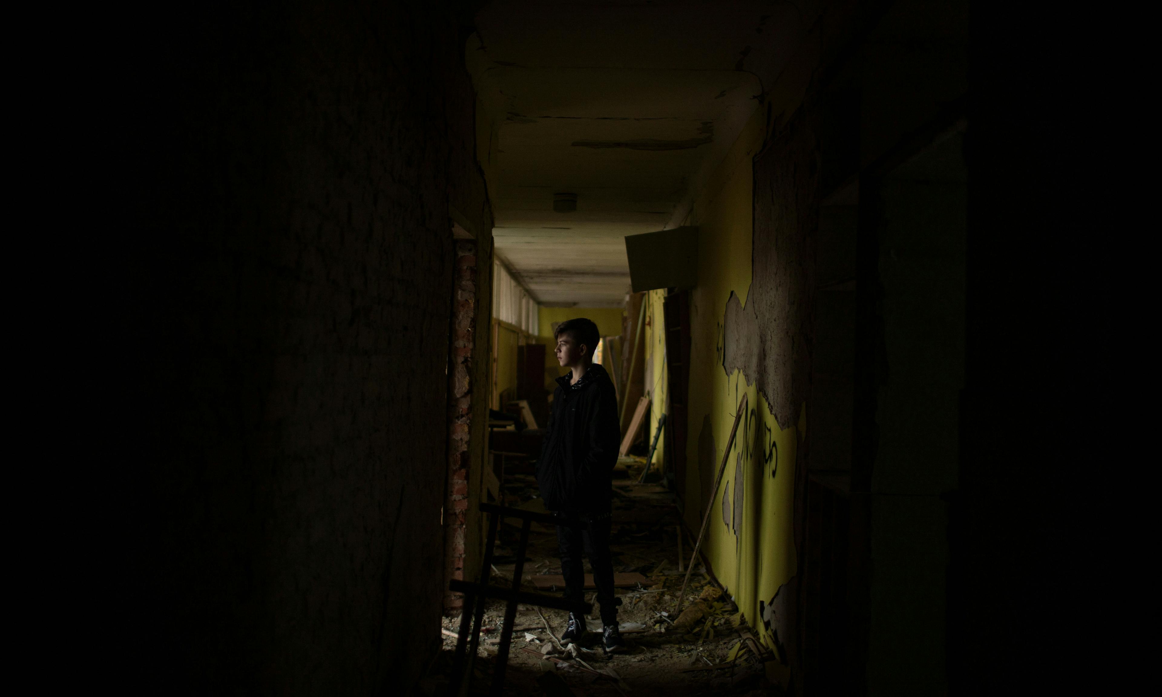 A young boy standing in the hallway of a destroyed school in Ukraine 
