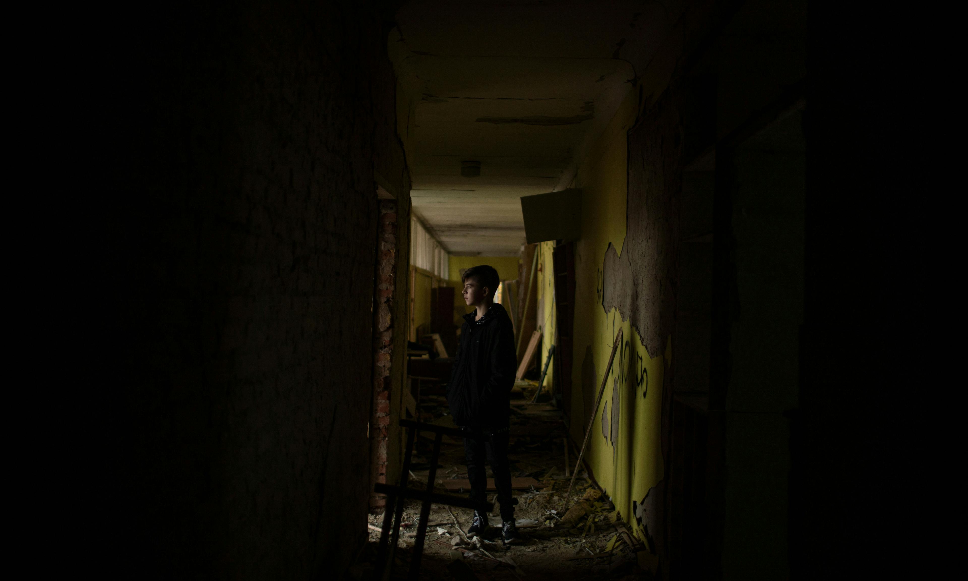 A young boy standing in the hallway of a destroyed school in Ukraine