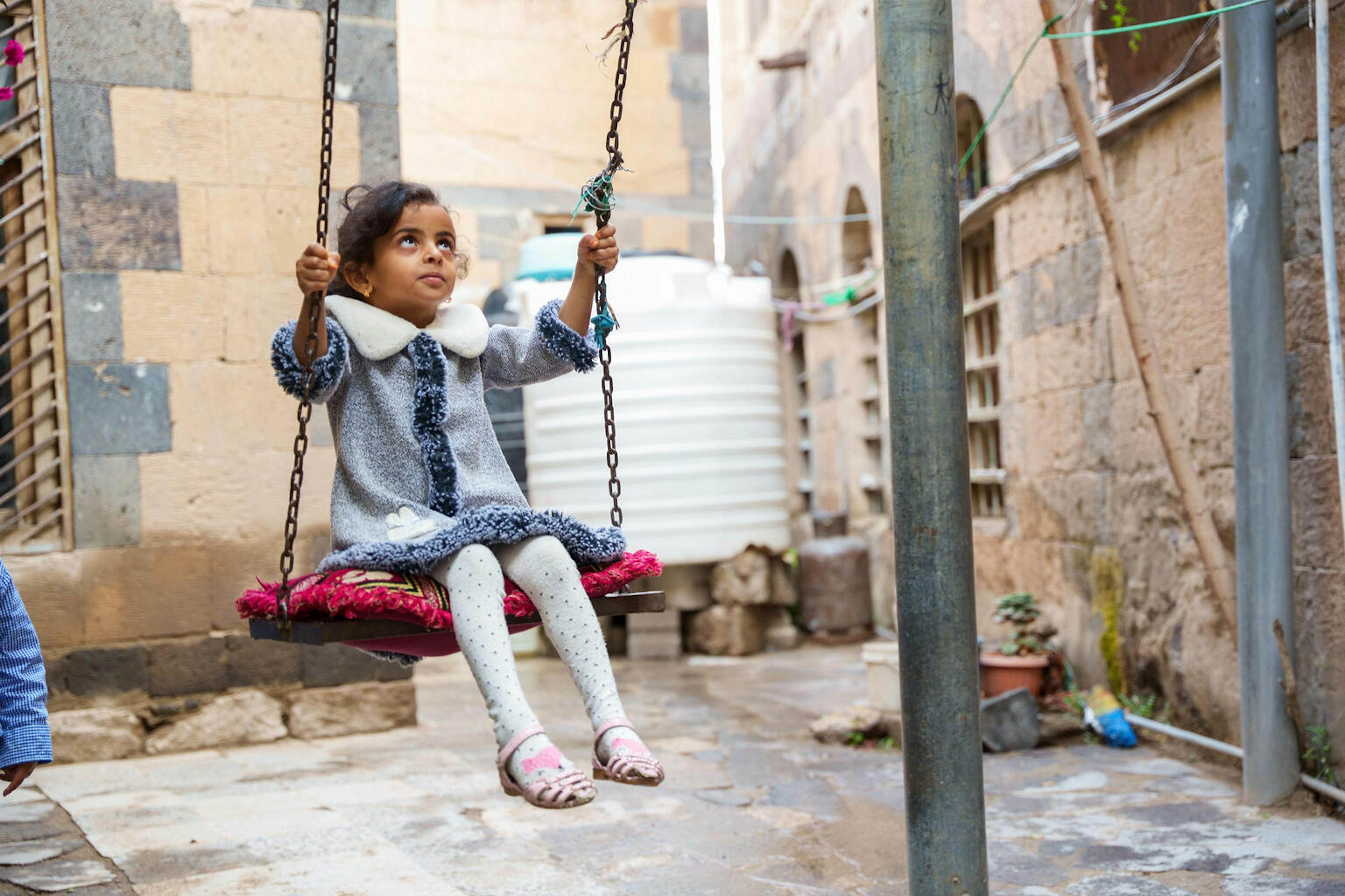 The 7-year-old daughter of Suroor Al-Shama’a swings in the front yard of their house in Dhamar Governorate, Yemen