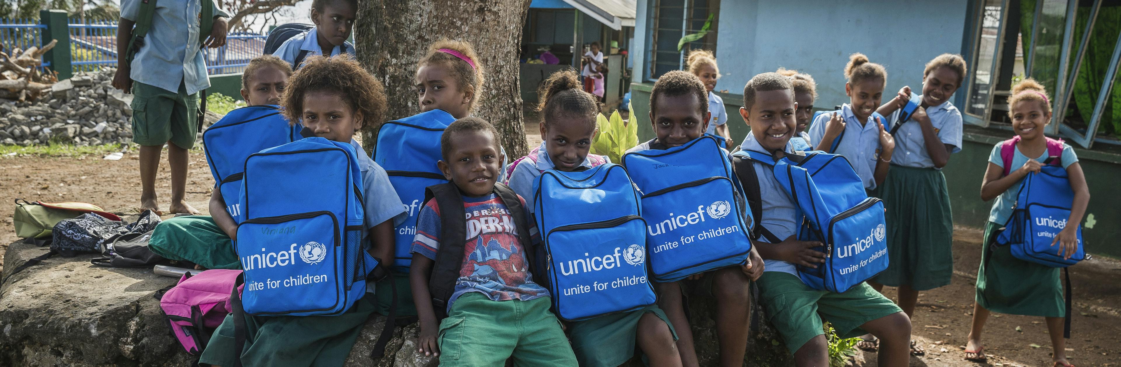 Children proudly hold their new school bags.
