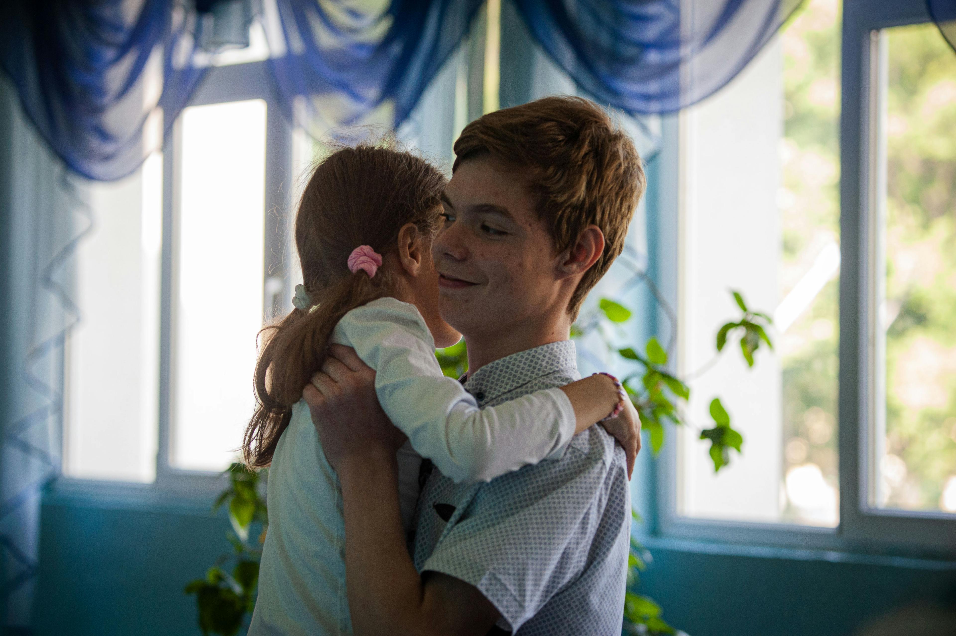 14-year-old Vanea hugs his 10-year-old sister Sasha in the school corridor. The siblings fled Zhytomyr, Ukraine as the fighting intensified along with their mother and grandmother.