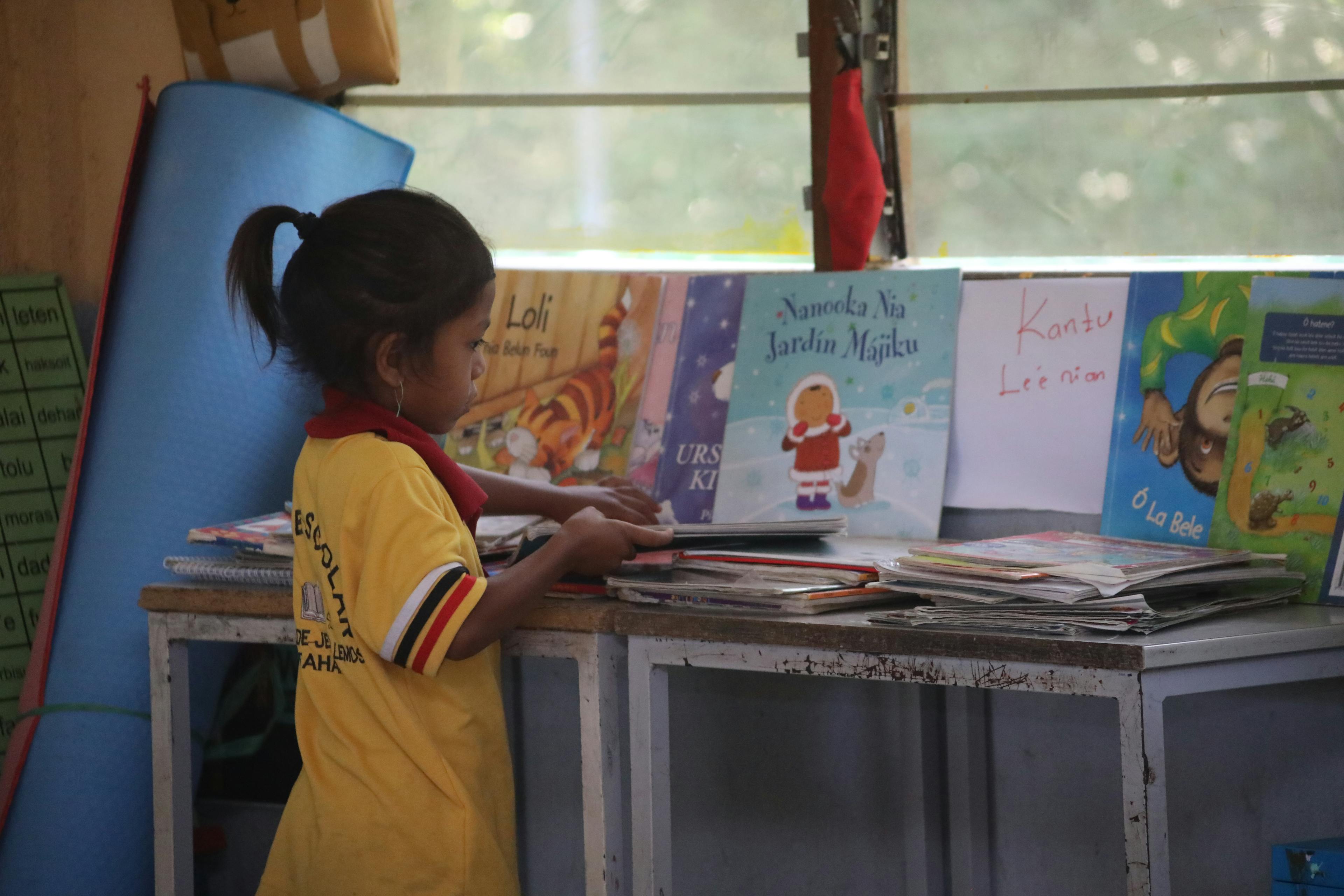 A young girl from Hi Preschool (about 30 minutes outside of Dili) deciding which children's book to read in class. These books, provided by the co-investment funding, are written in the Tetum language and include stories that are culturally relevant for children in Timor-Leste.