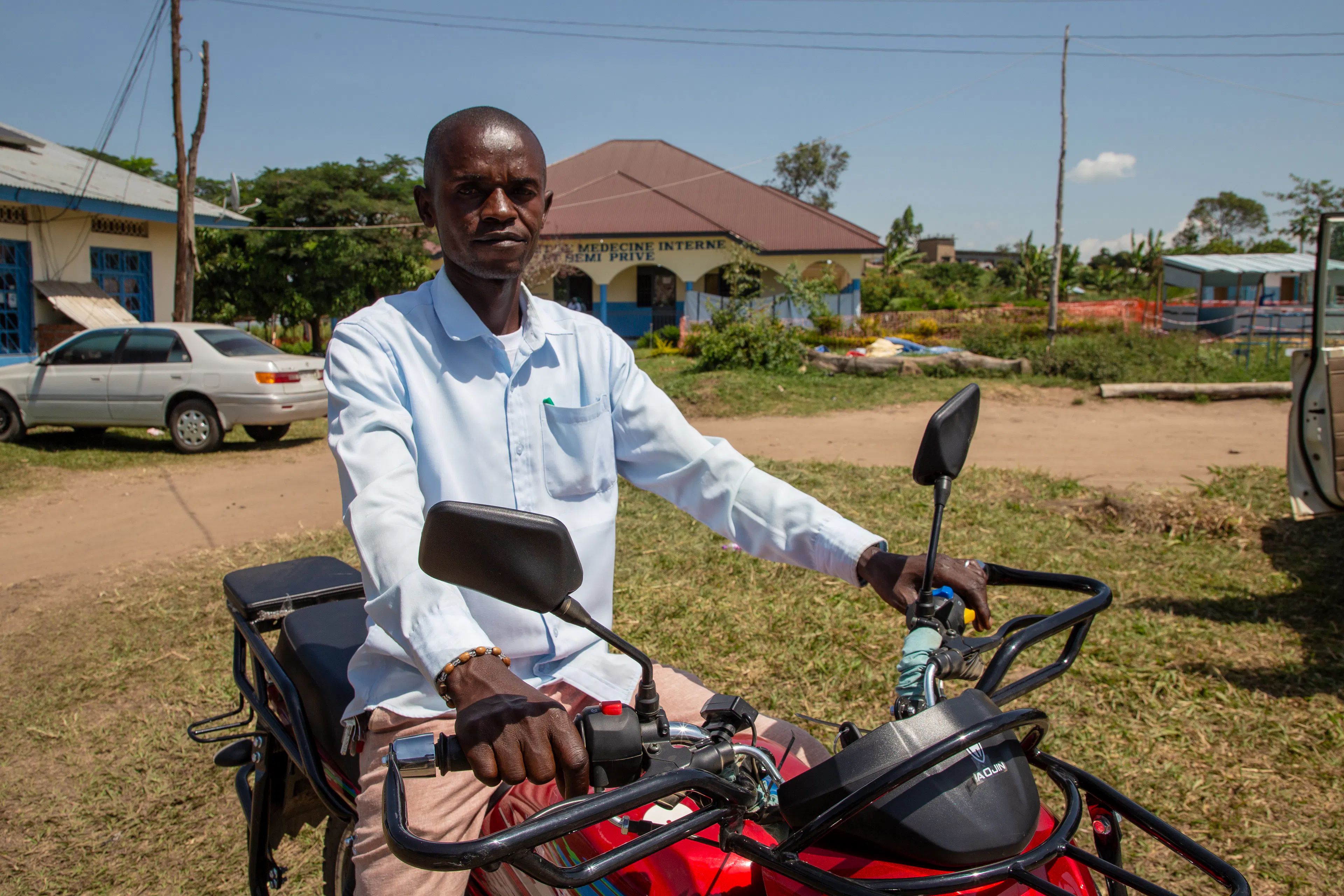 Dieudonné Bamuhiga, Mental Health and Psychosocial Support Assistant, stands on a motorcycle to raise awareness about Ebola at Rwampara, Ituri Province, DRC, on June 8, 2026.