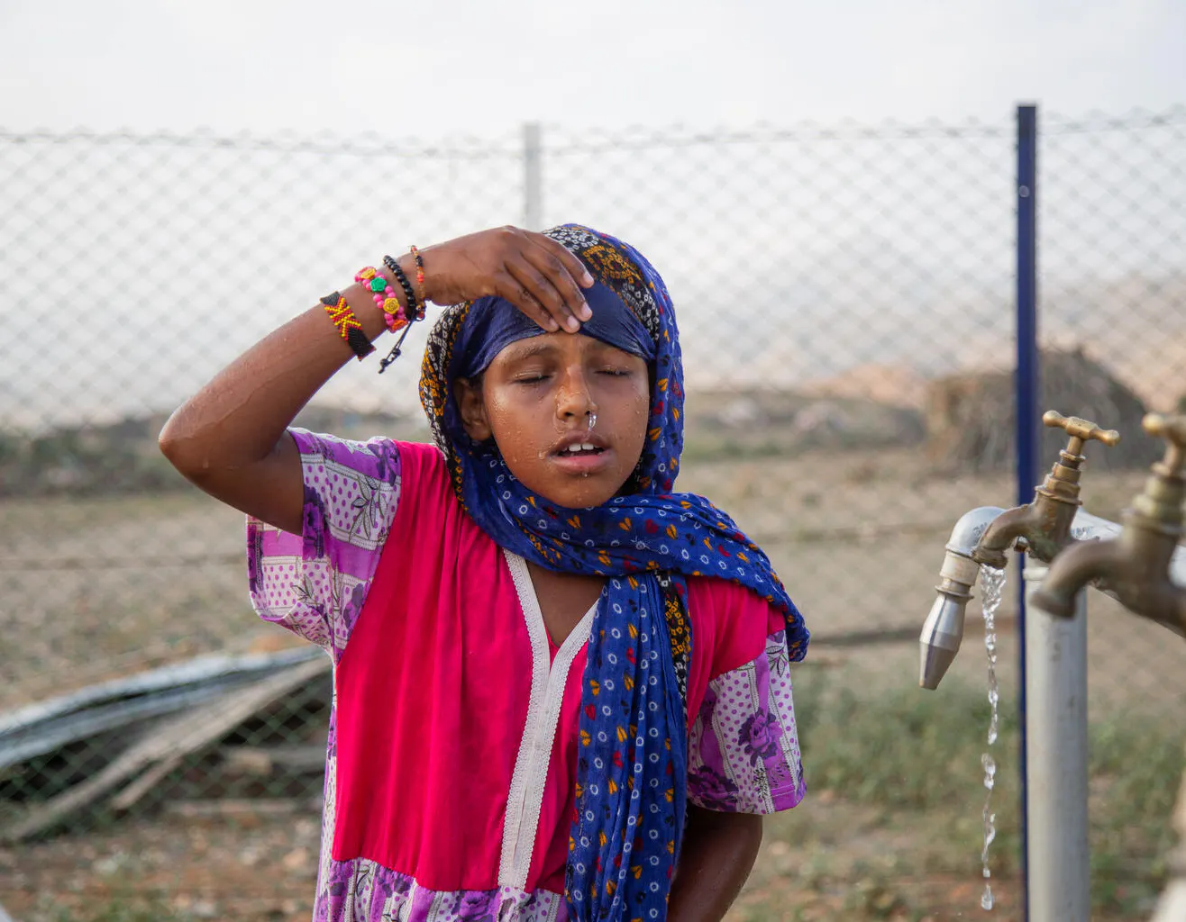 7-year-old Madina Mohamed Awad wets her face with clean water at a new water station in the small village of Gelhanty in Agig locality, Red Sea state.