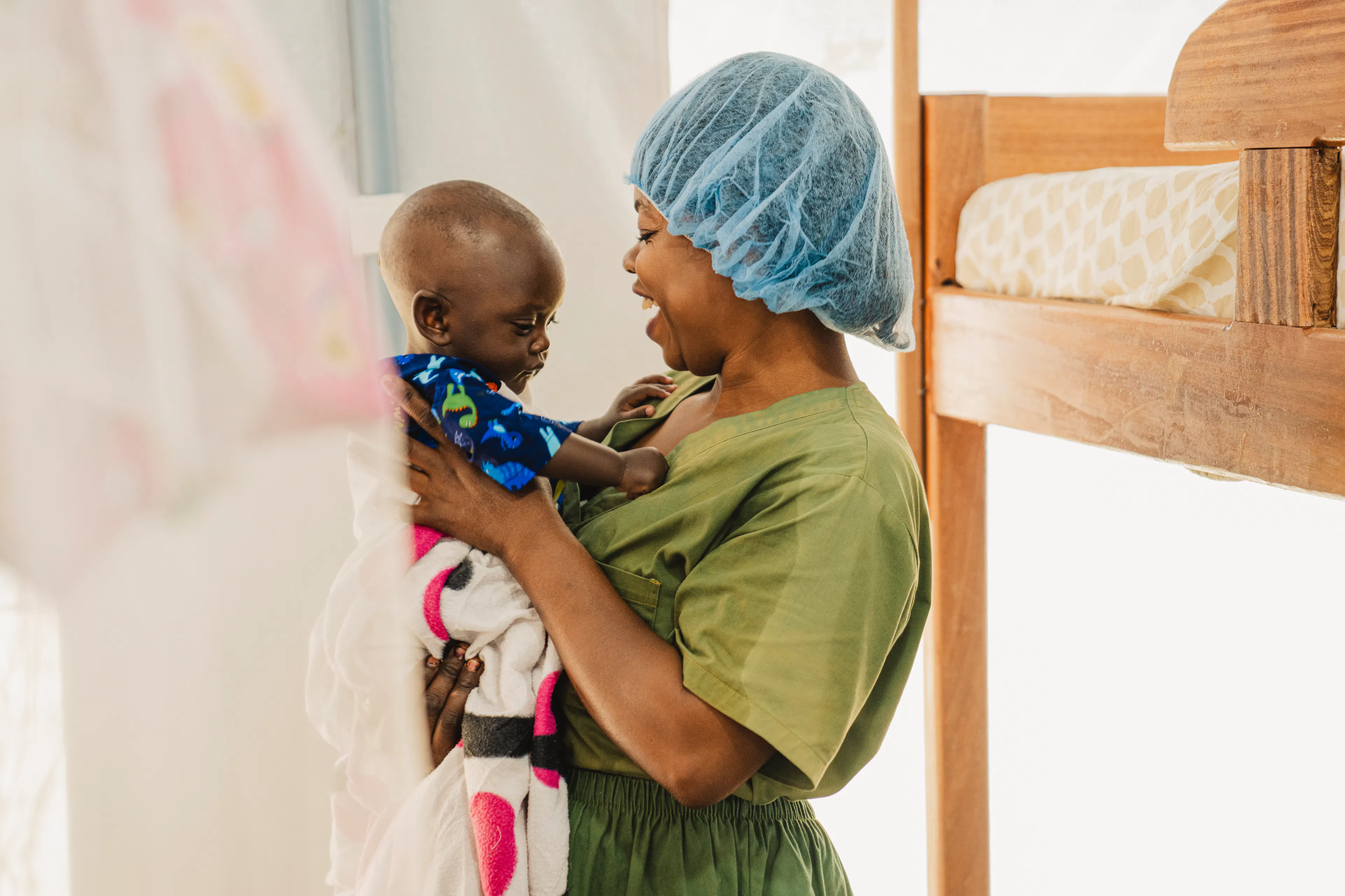 Wivine Kabala , is with a child at the nursery for children whose parents are hospitalized at the Ebola Treatment Center in Bunia, Ituri province, Democratic Republic of the Congo, on June 24, 2026.
