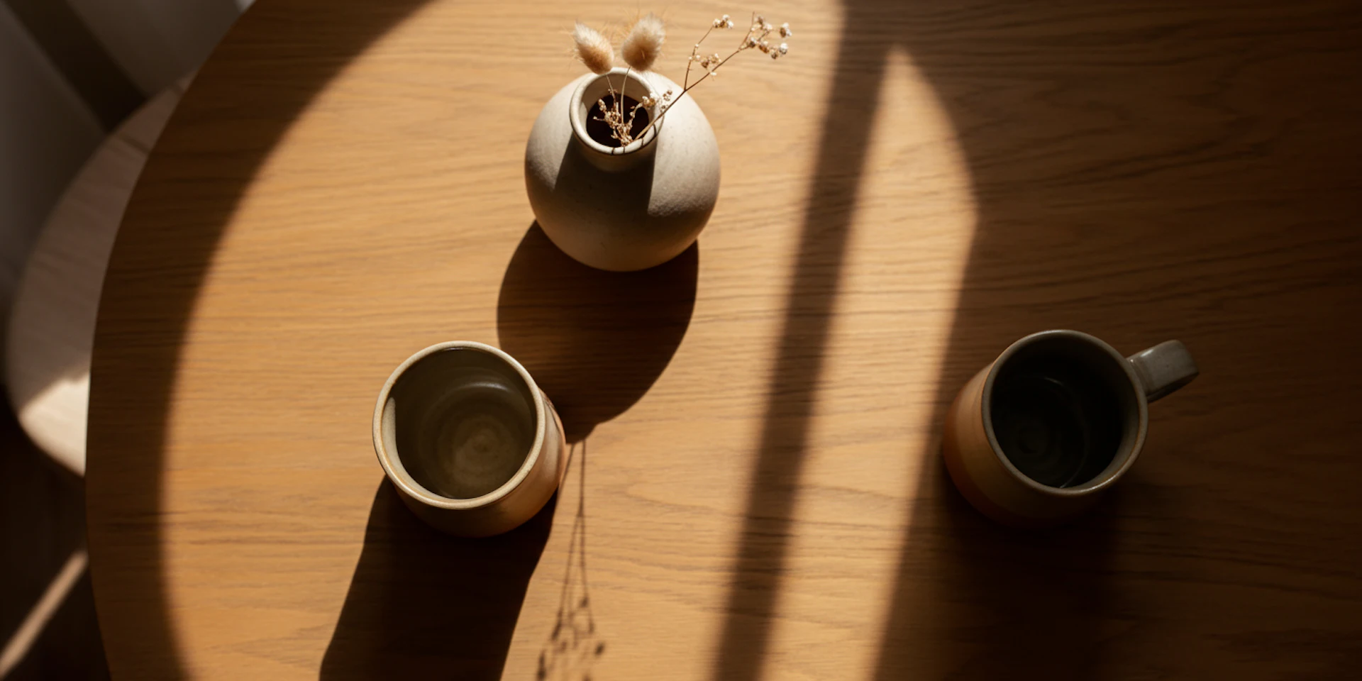 A minimalist still life image of coffee mugs and a ceramic vase, reflecting a warm, inviting atmosphere that promotes mental wellbeing.