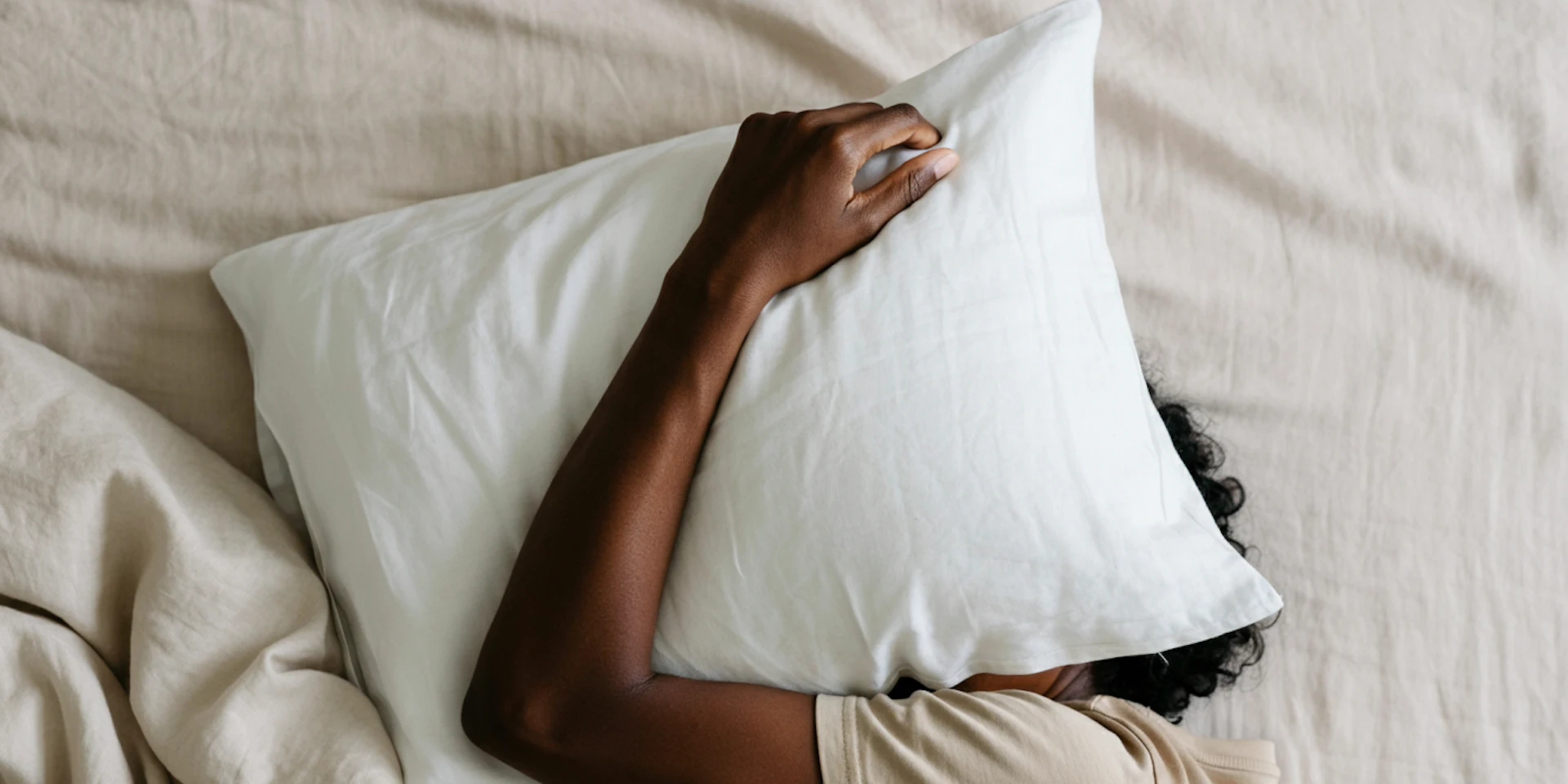 A peaceful indoor scene with a person resting on a bed, symbolizing the importance of relaxation and recovery in workplace mental health.