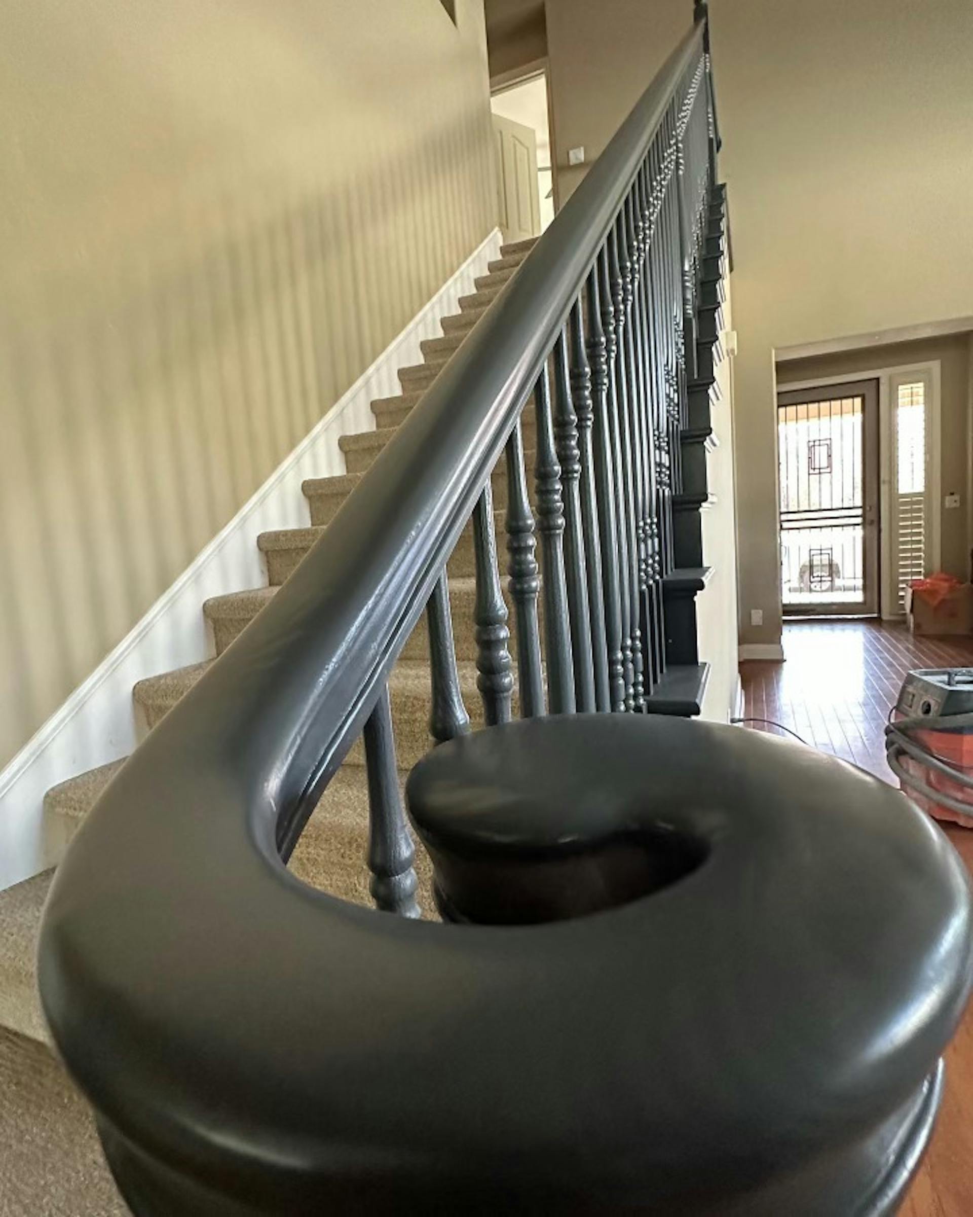 A dark colored banister inside of a well lit home