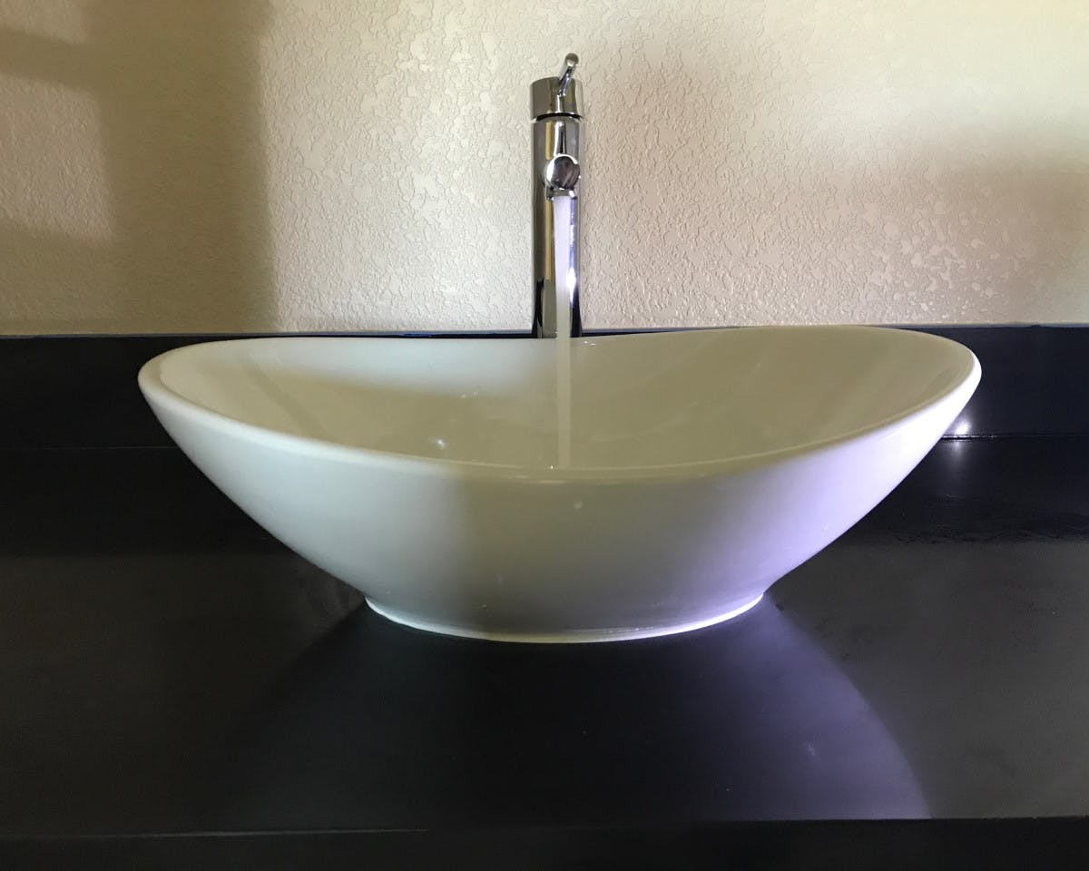 Water running out of a sink into an above counter sink bowl
