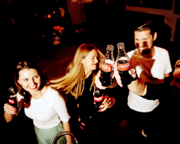 Gruppe von Menschen tanzt im Club mit Coca Cola Flaschen.