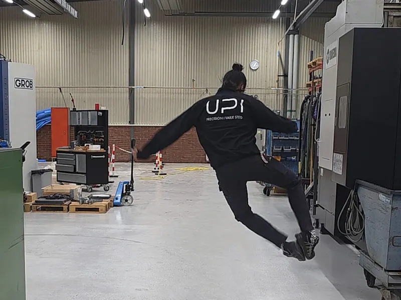 UPI-medarbetare hoppar av glädje med klackarna ihop, fotograferad bakifrån. En bild som förmedlar arbetsglädje och gemenskap.