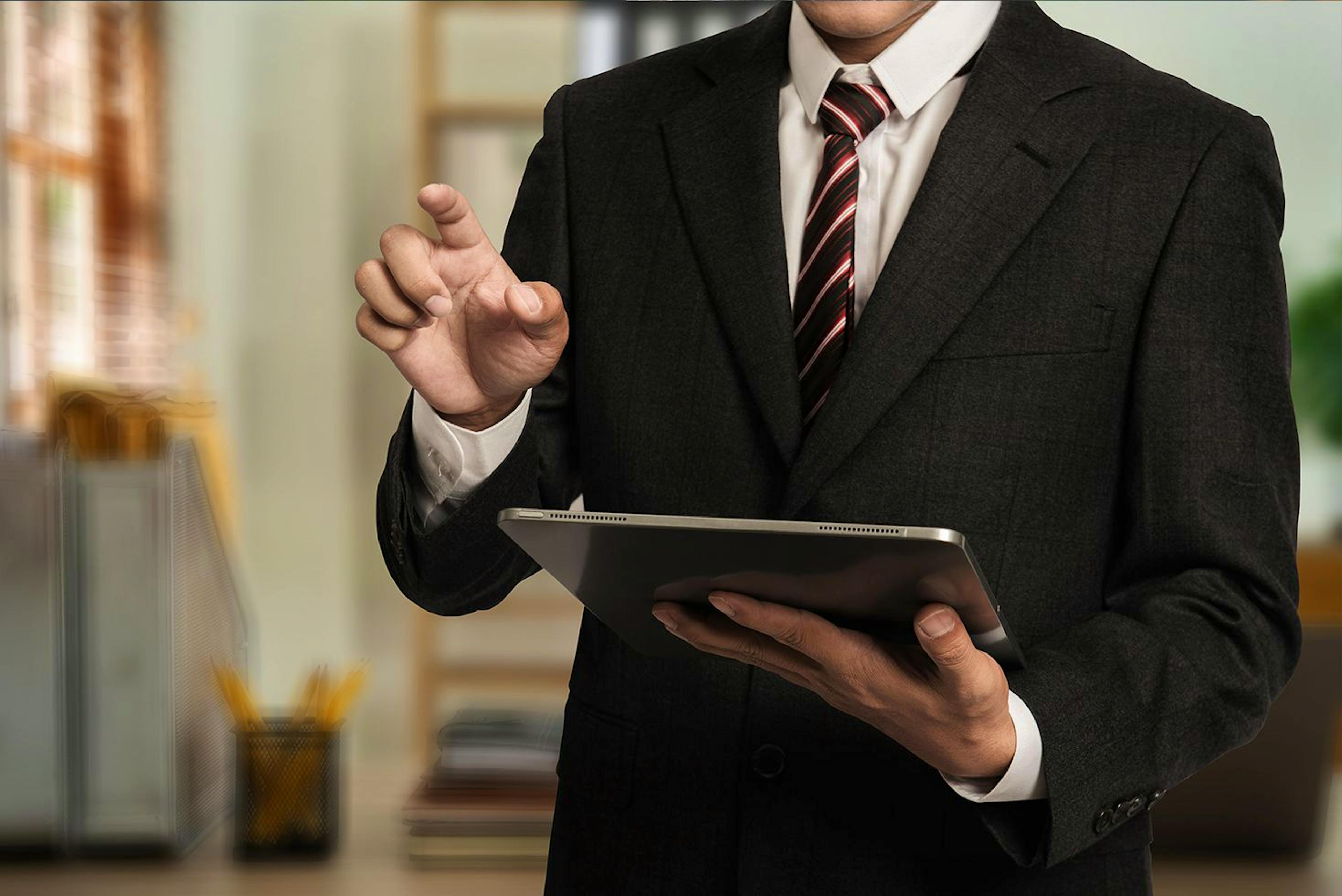Advogado com um tablet na mão representando o tema consulta de processos.