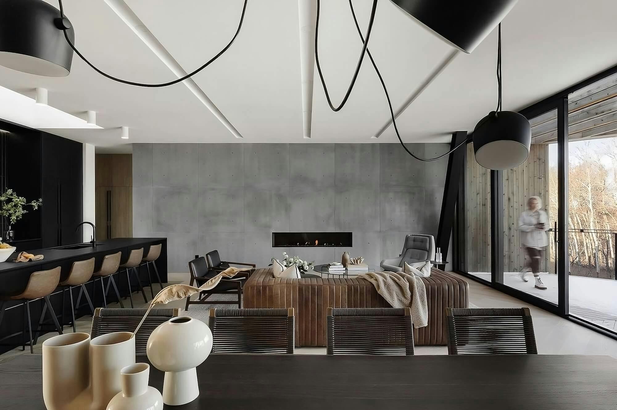 A modern room with a concrete wall, white ceiling, and dark furniture, alongside a long window.