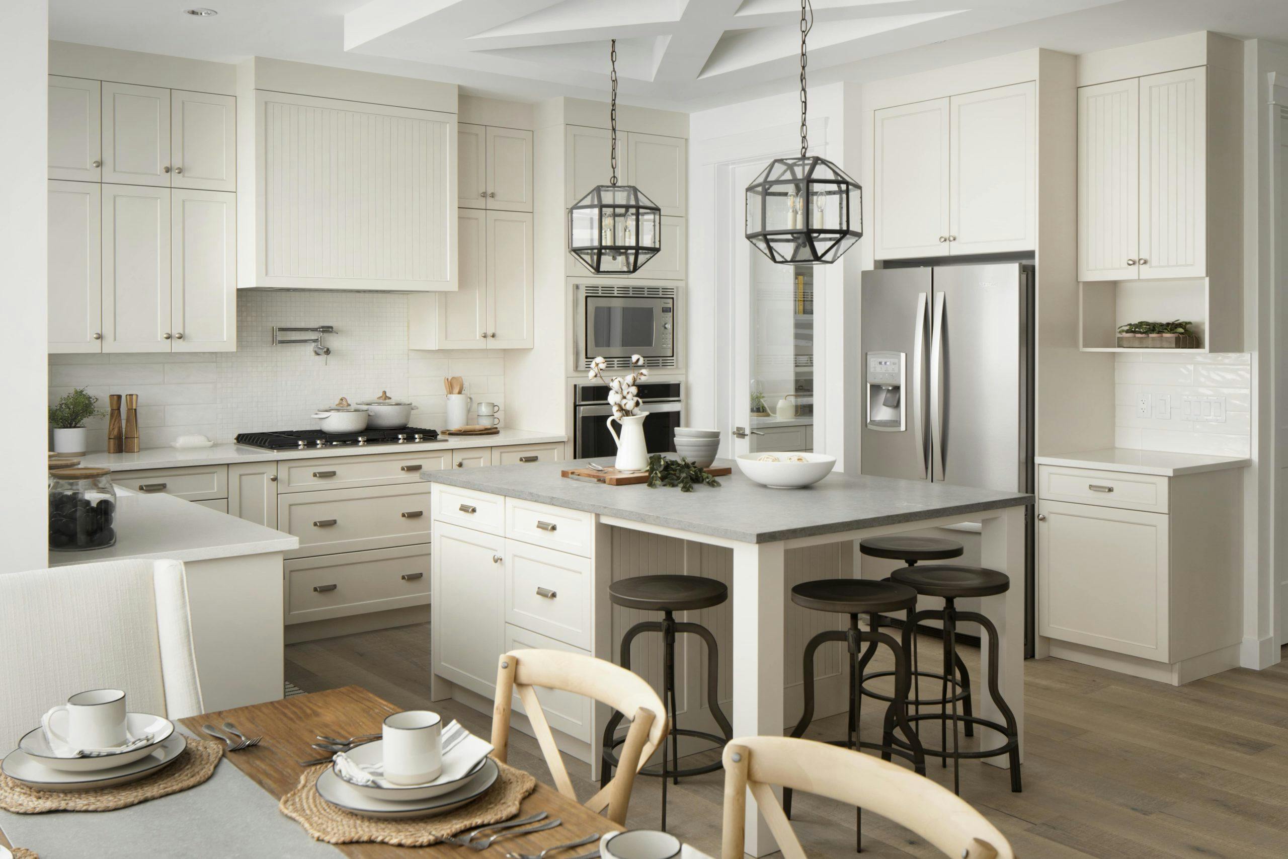A white showhome kitchen, with flowers in a vase set on the kitchen countertop.