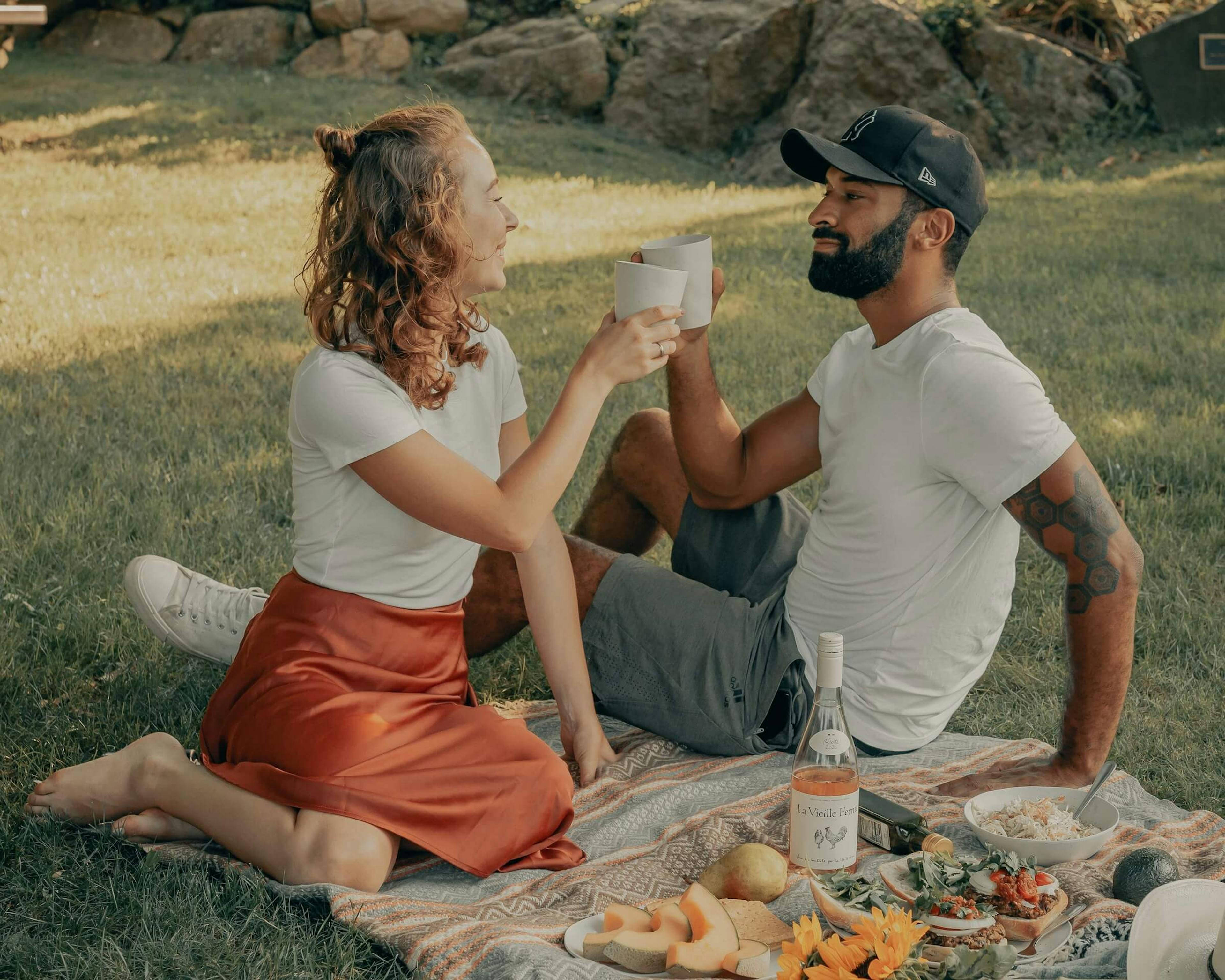 A couple enjoys a picnic on the grass near some rocks