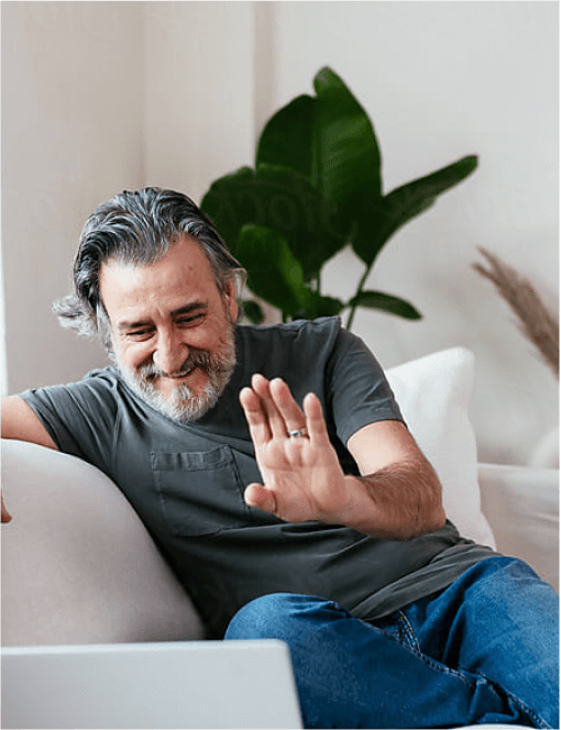 Man waving at camera on a sofa