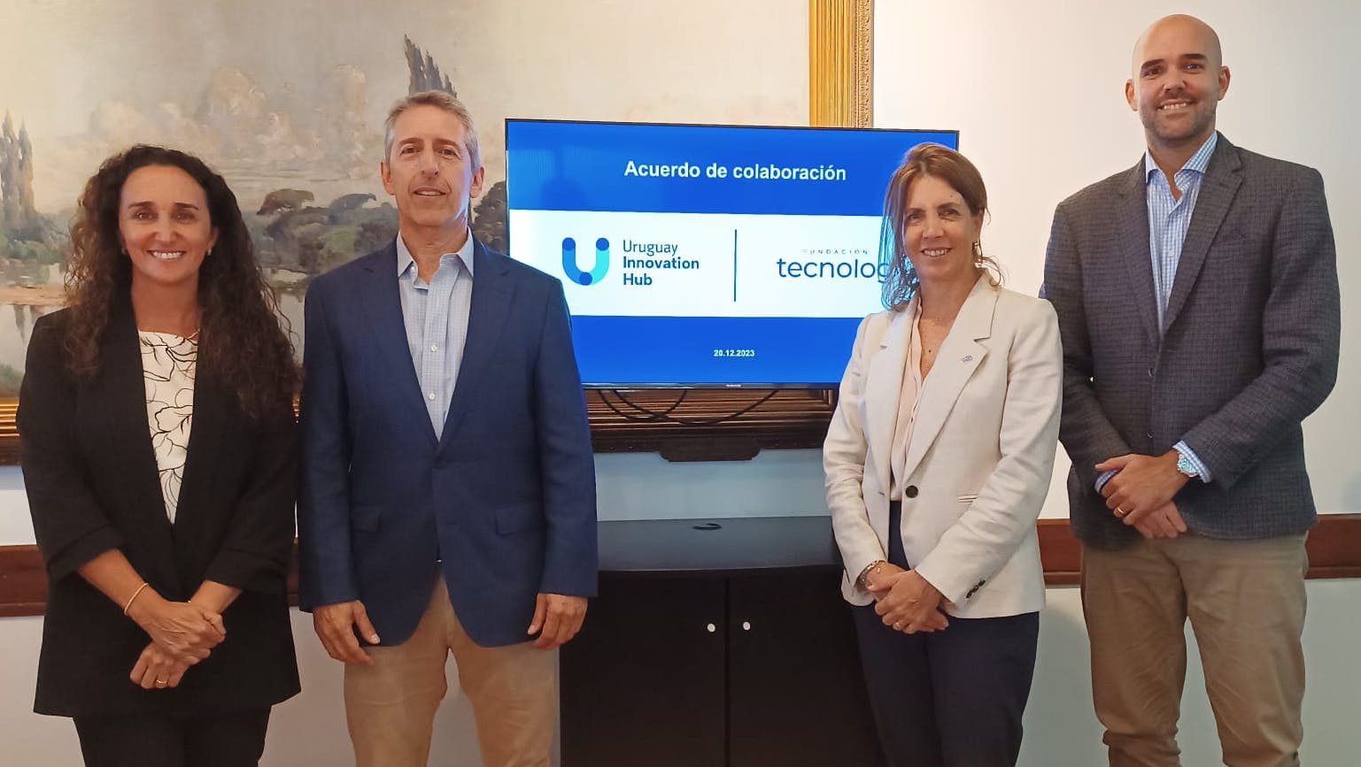Representantes de Uruguay Innovation Hub y Tecnolog posan para la foto. Detrás una pantalla con los logos de ambas instituciones