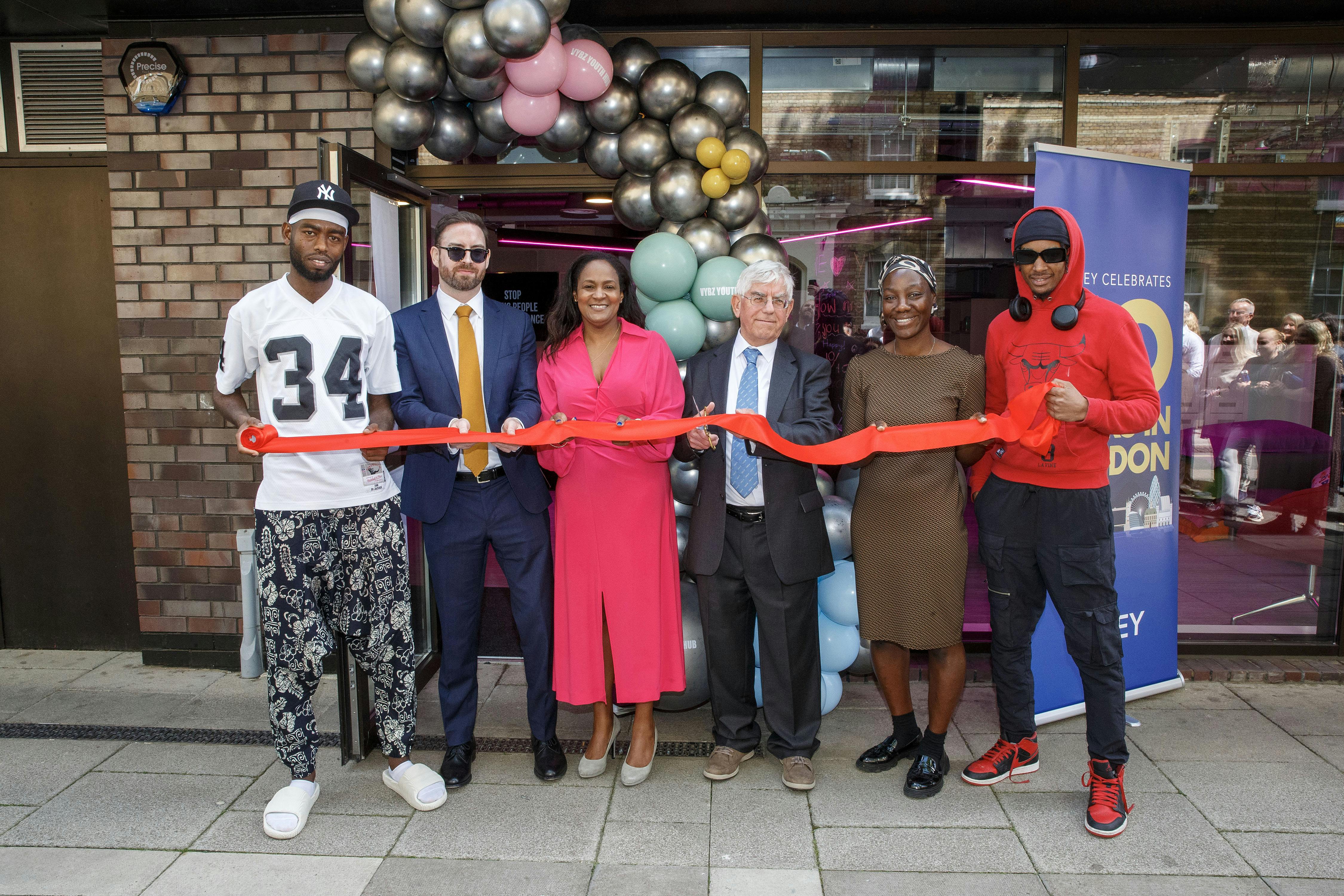 A group of people holding a ribbon ready to cut