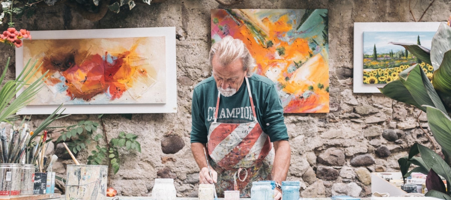 An older man painting glass in a studio