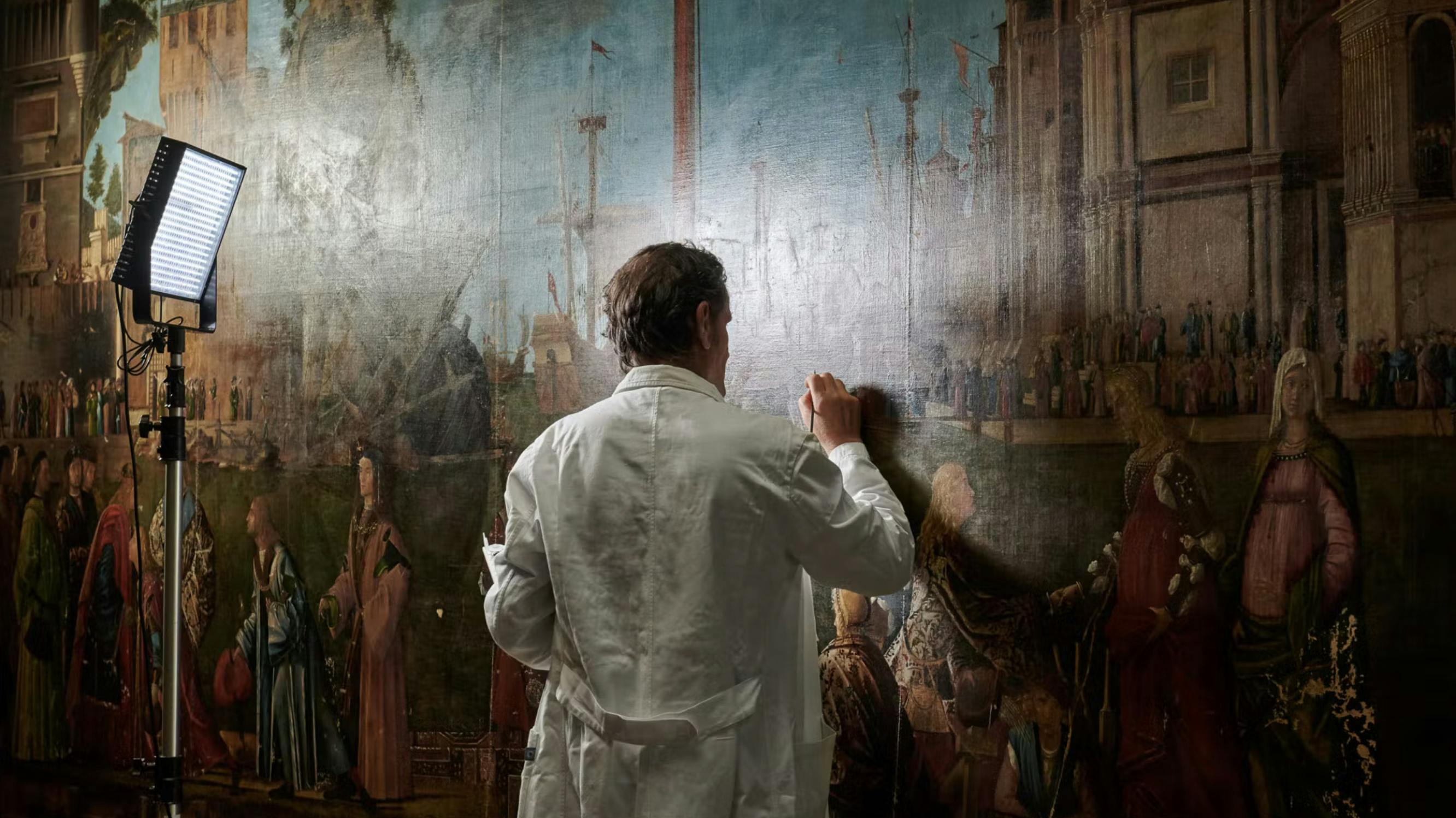 An artist carefully undertaking restoration of Vittore Carpaccio's painting 'Incontro e partenza dei fidanzati'