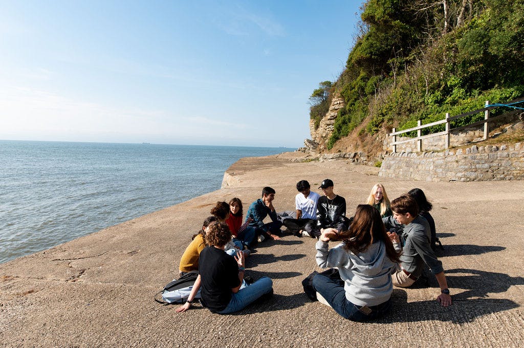 students sitting together at the seafront