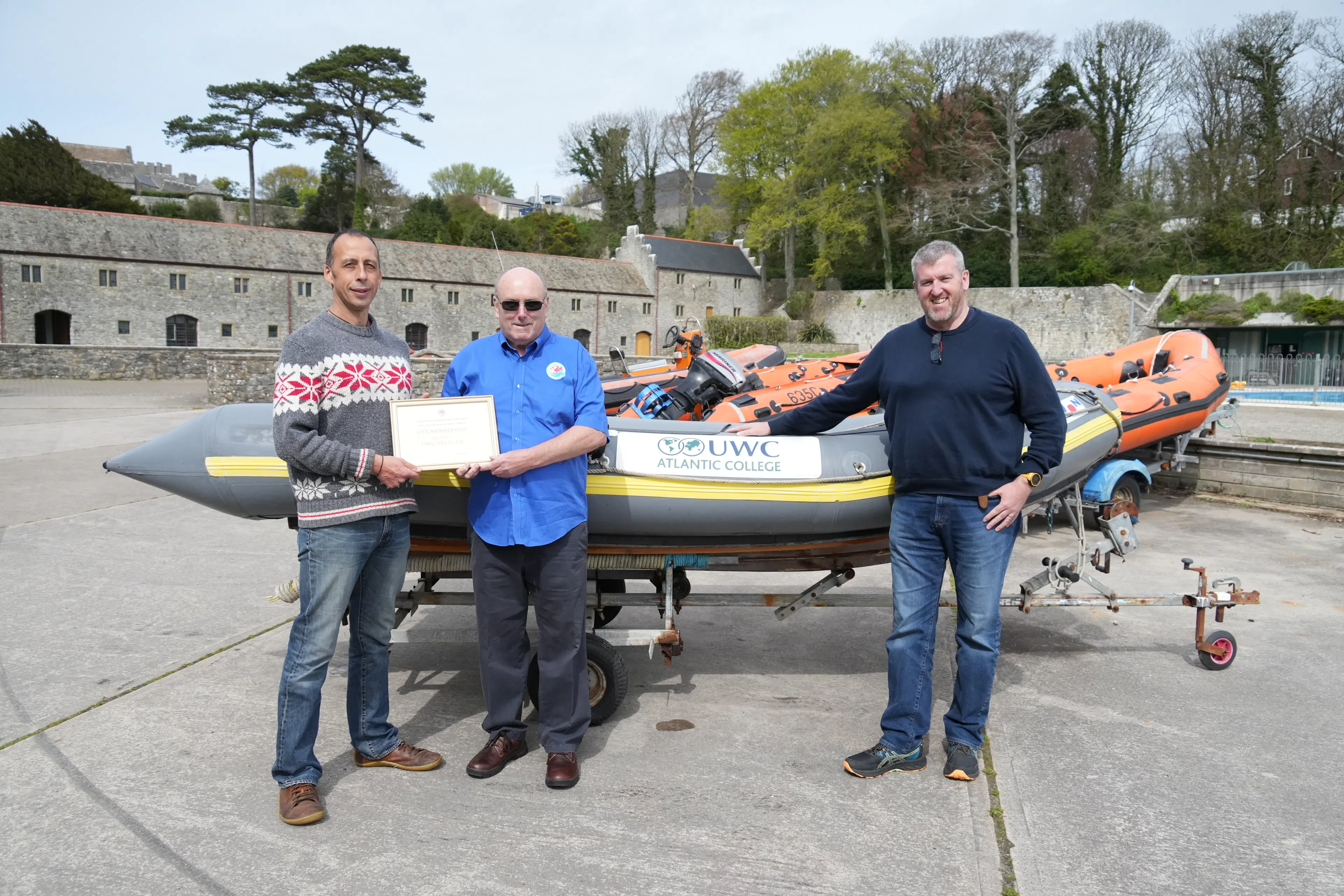 SLSA people awarding UWC Atlantic lifetime membership in front of a RIB boat at St Donats Castle seafront