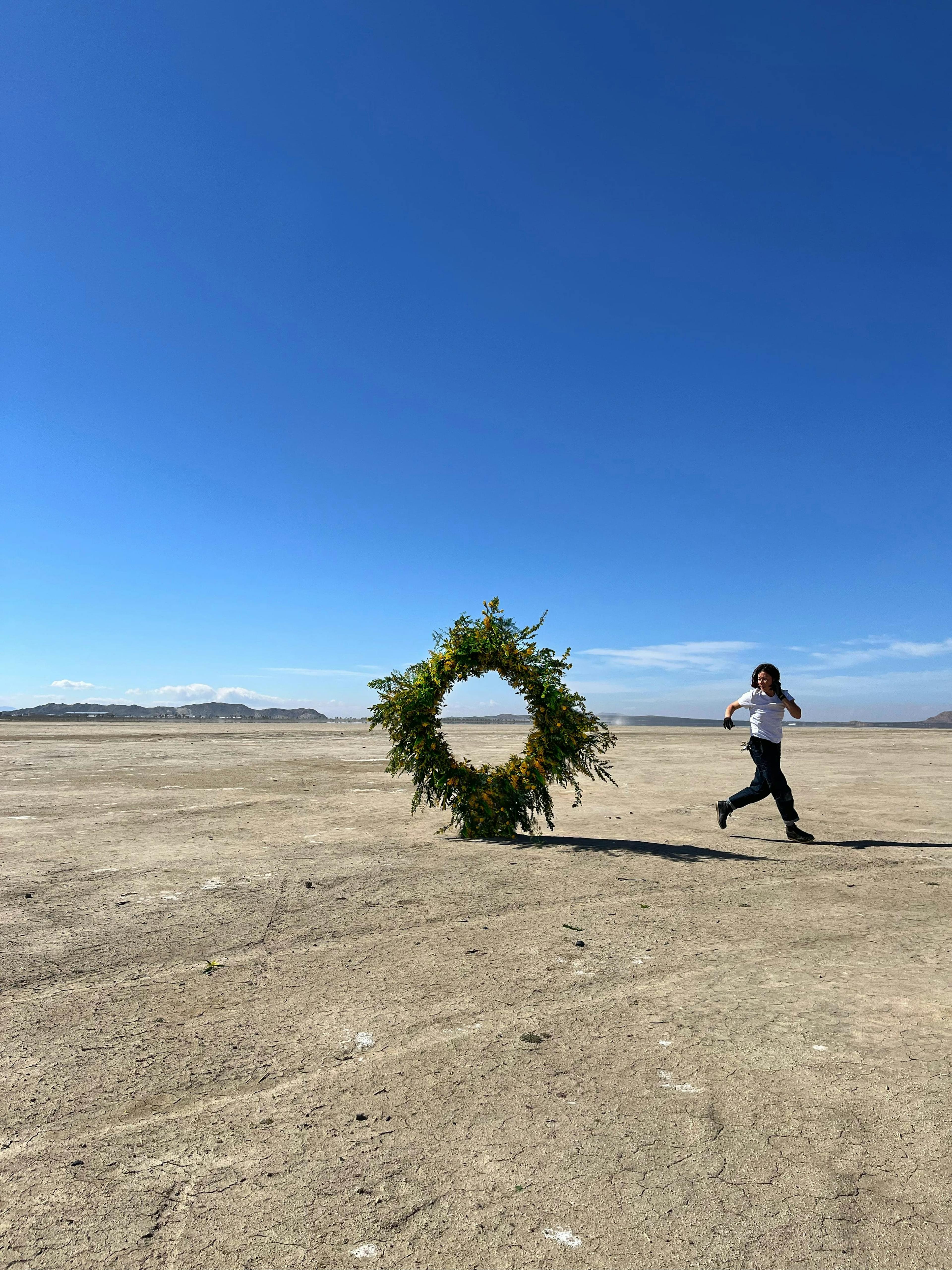 A women running away from a large round arrangement of yellow flowers with green foliage.