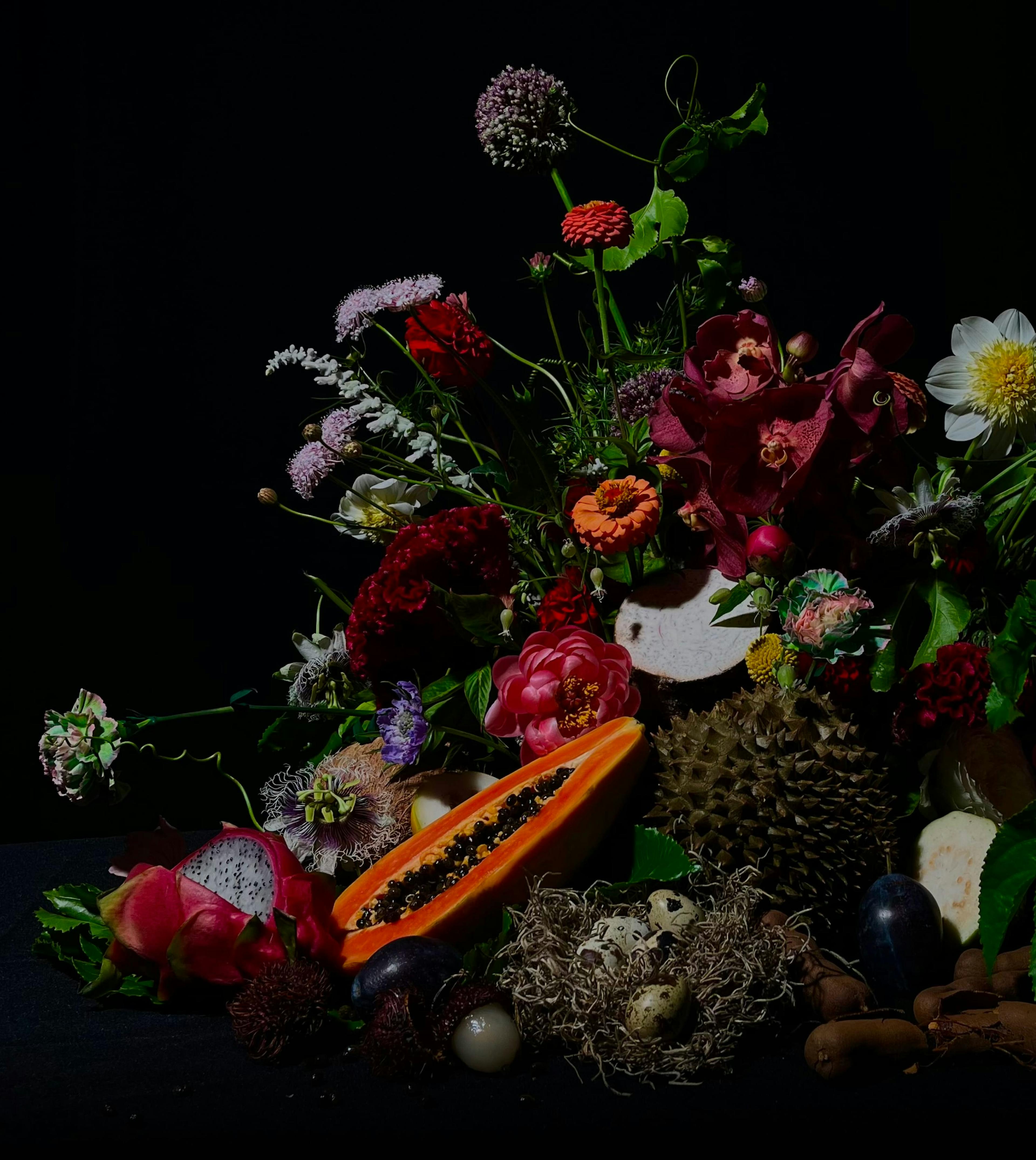 A close up of an arrangement of flowers and fruit.