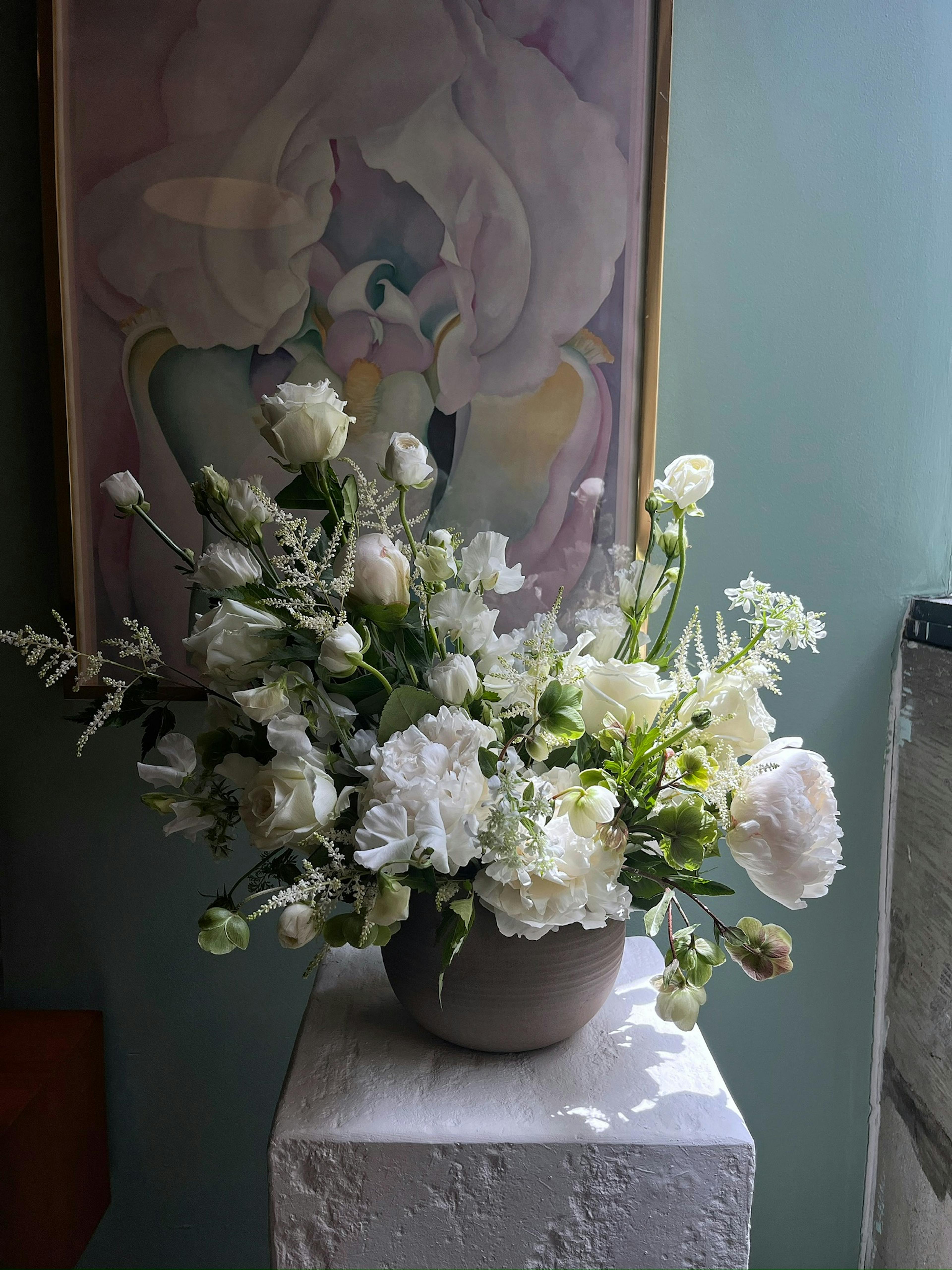 A beautiful, delicate arrangement of white flowers in front of a light blue wall