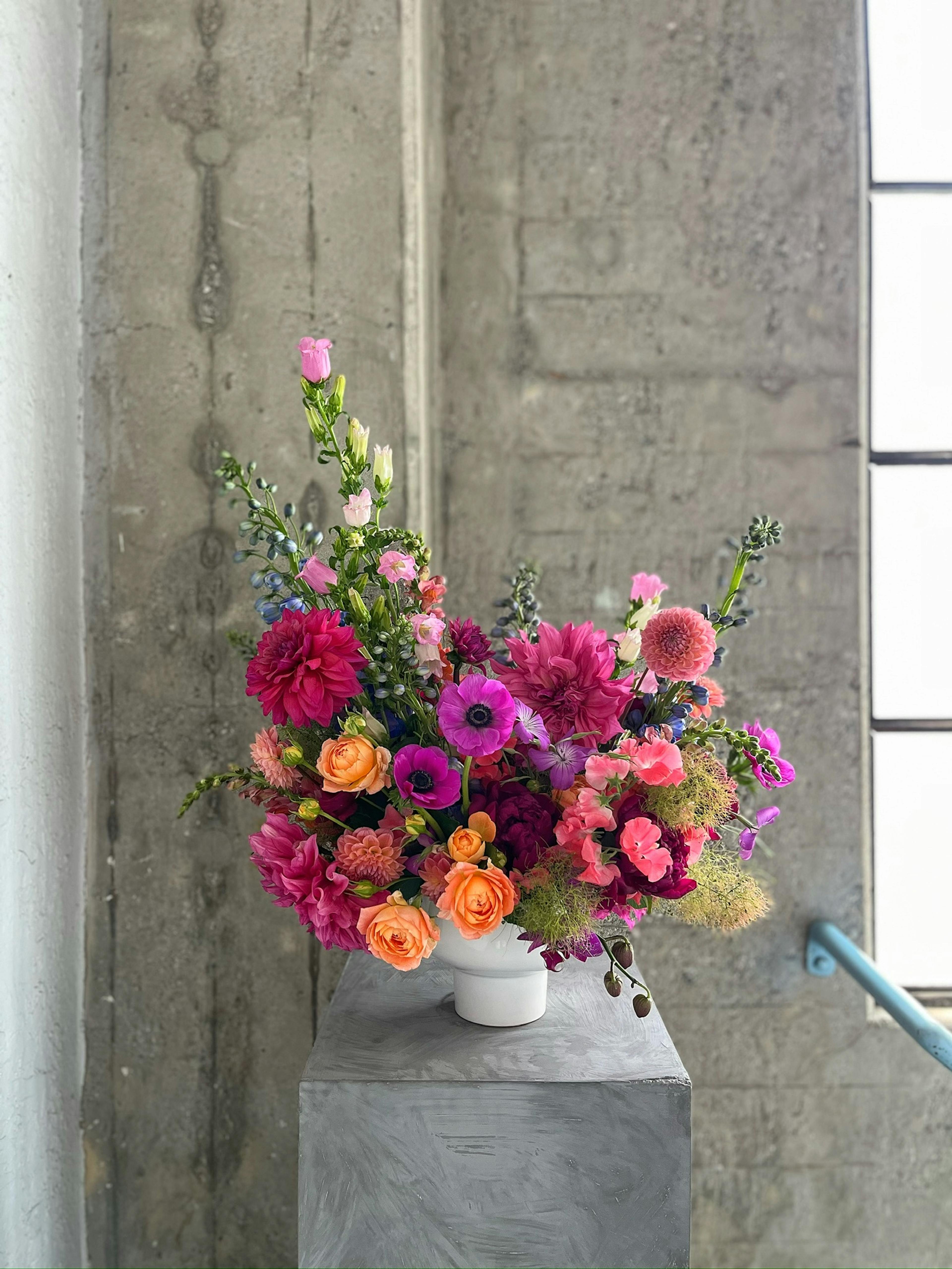 A beautiful arrangement of pink and orange flowers in front of a concrete wall