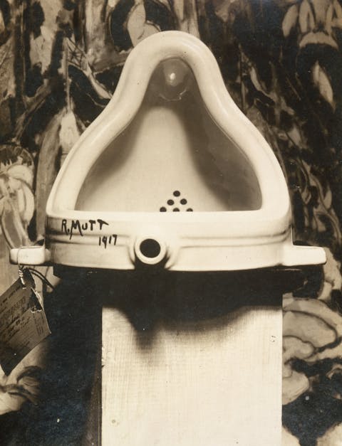 Marcel Duchamp, 1917,Fountain at the291 (Art Gallery)following the 1917 Society of Independent Artists exhibit, with entry tag visible. The backdrop isThe Warriors by Marsden Hartley
