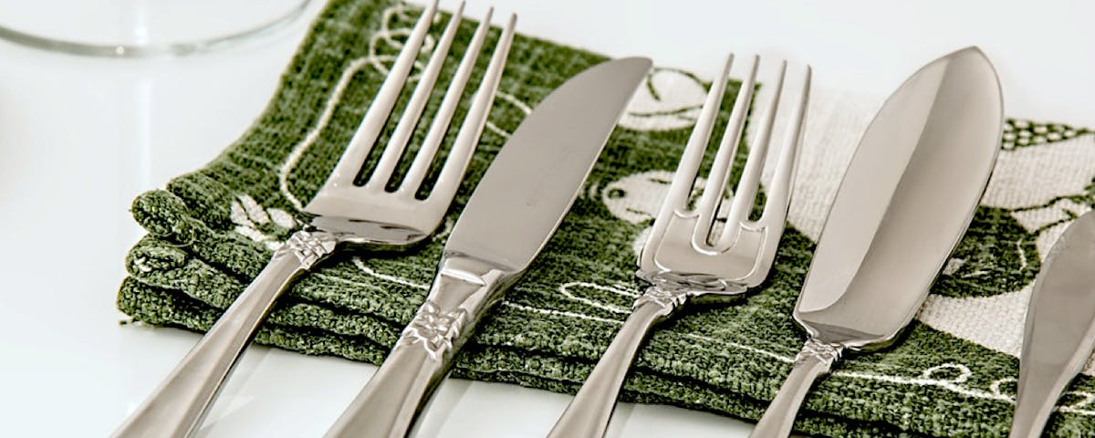 set of silver flatware on green printed napkin