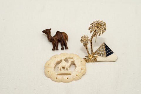 Pyramid and camel- themed grouping of pins and brooches
