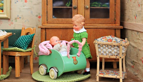 Girl and infant doll inside doll house