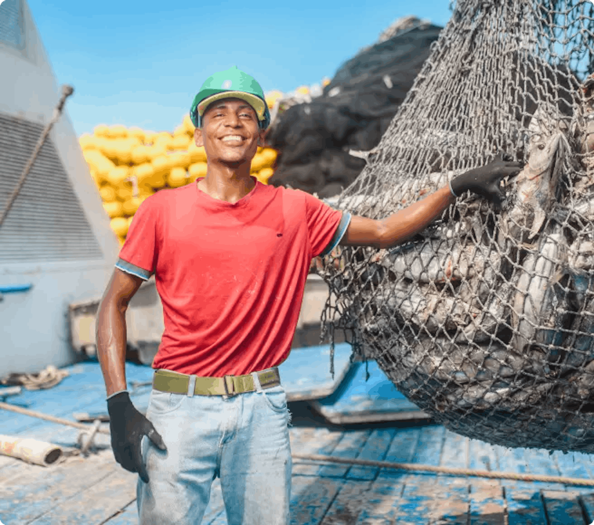 Trabajador pesquero sonriendo junto a una red llena de atunes