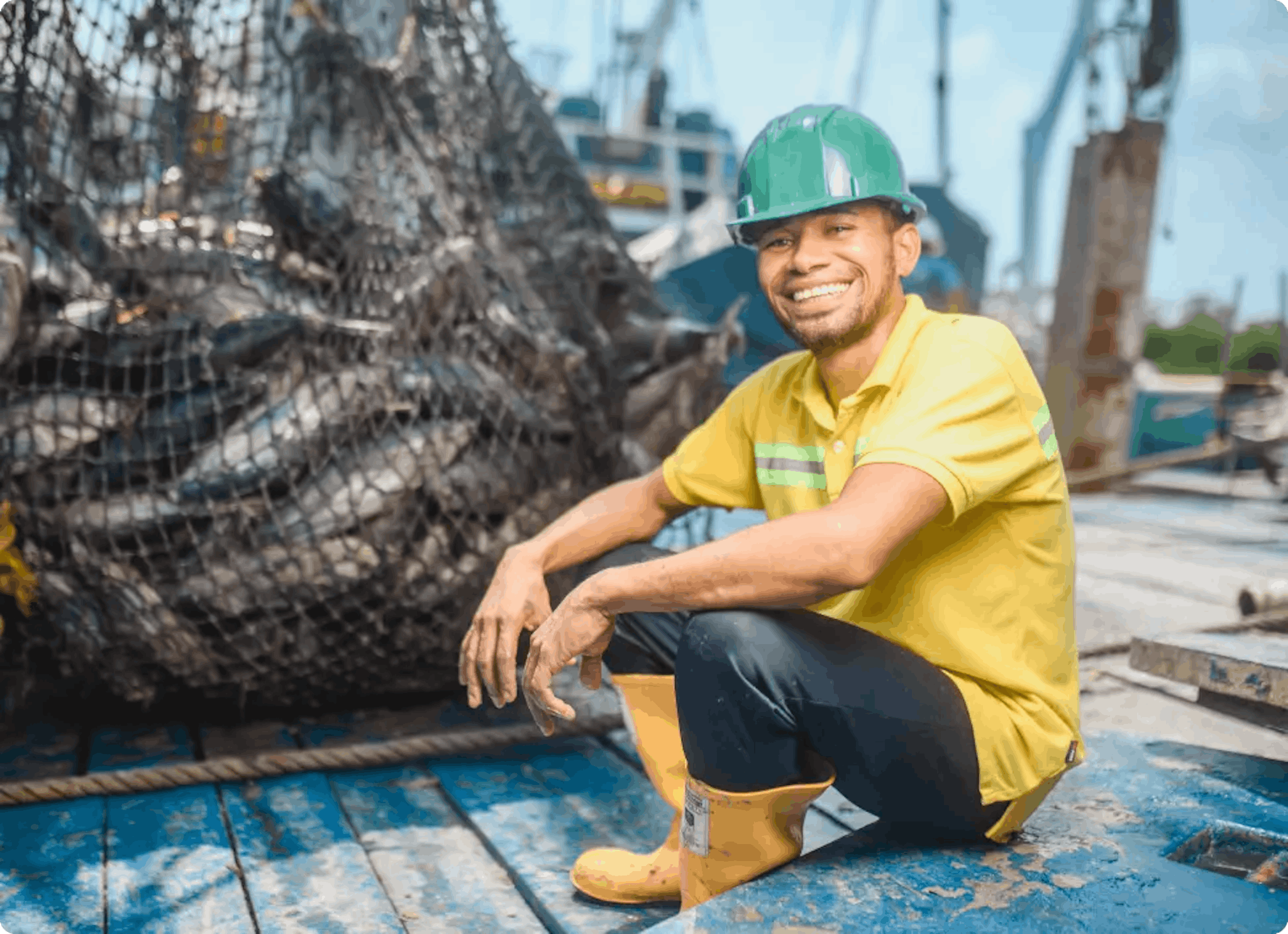 Trabajdor pesquero sonriendo junto a una red llena de atunes