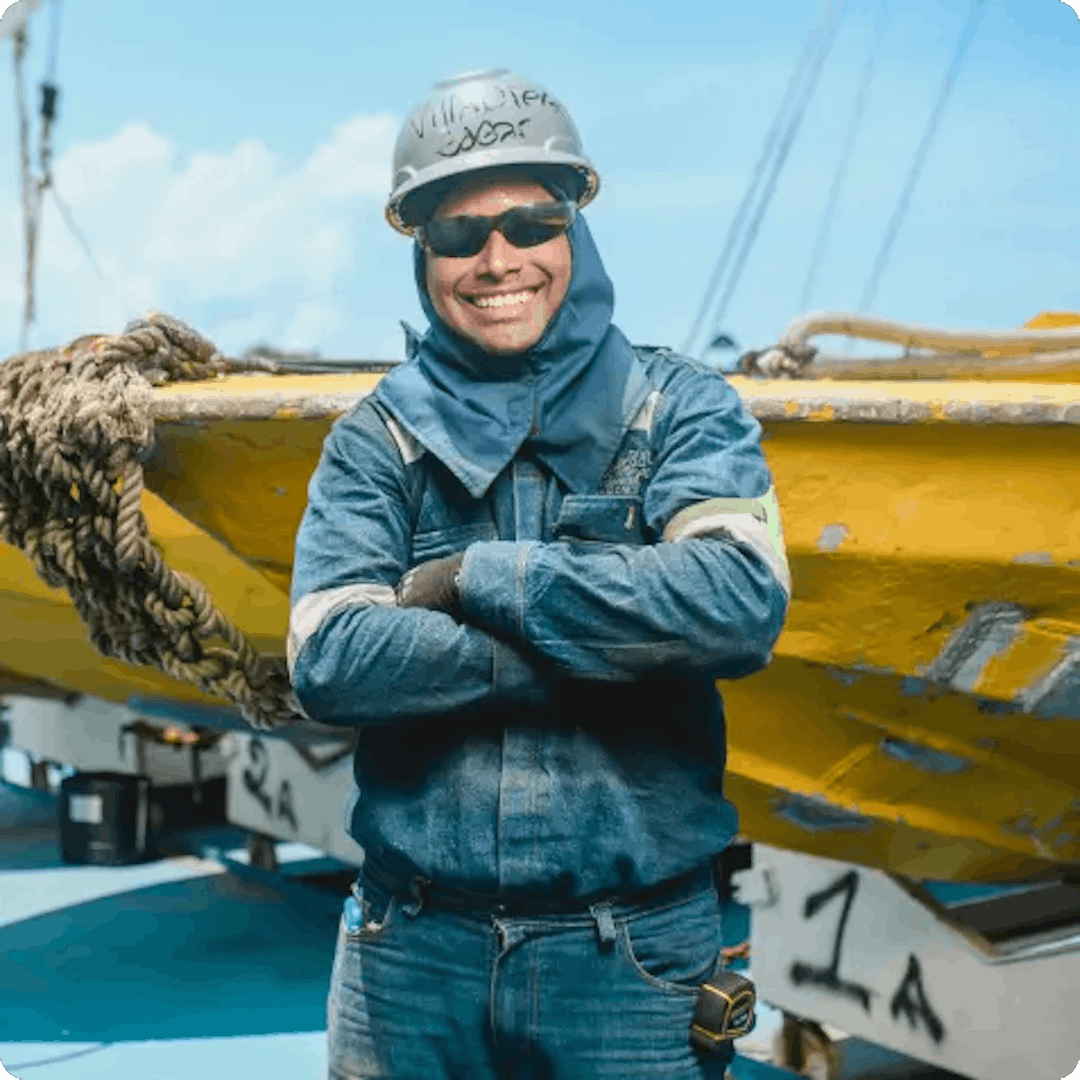 Trabajdo sonriendo de fondo una lancha pesquera