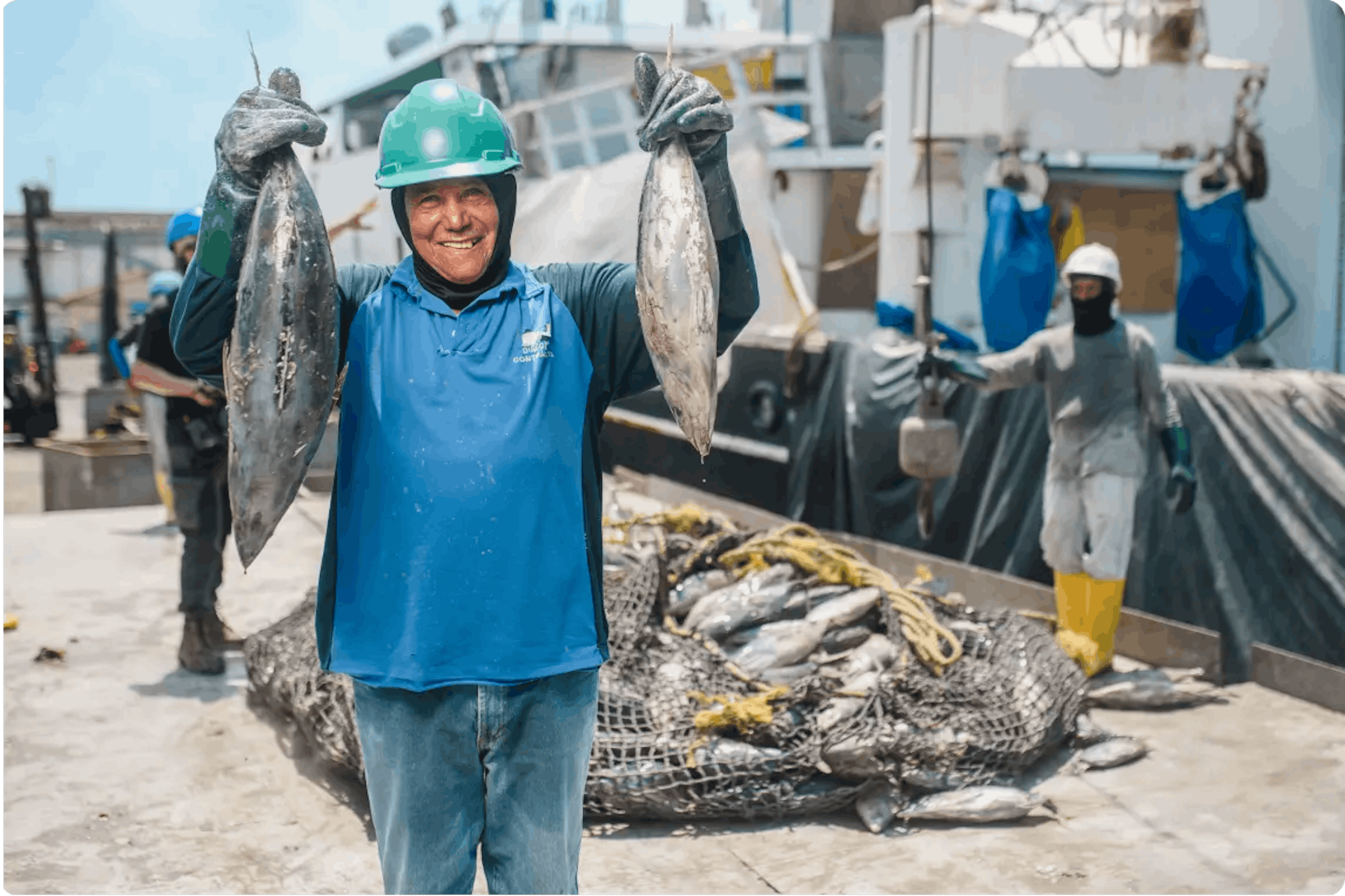 Trabajador pesquero sonriendo con dos atunes en sus manos