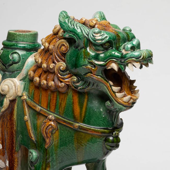 A pair of ferocious green and yellow glazed stoneware lions