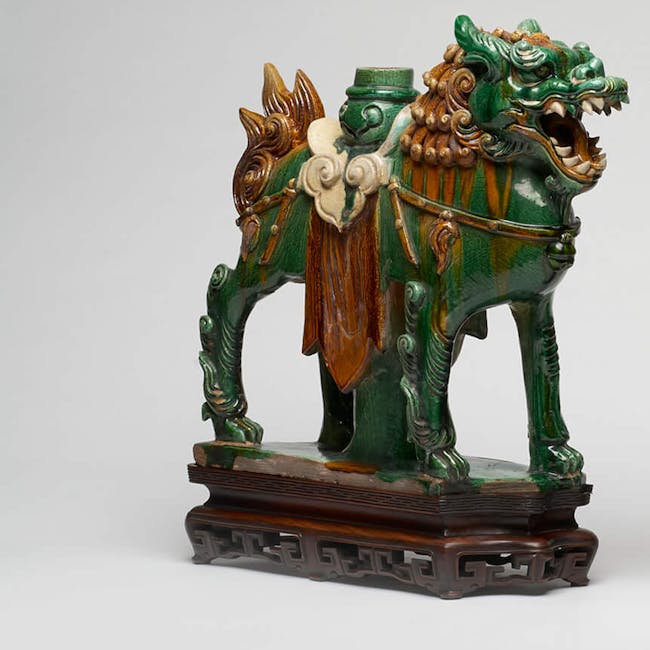 A pair of ferocious green and yellow glazed stoneware lions